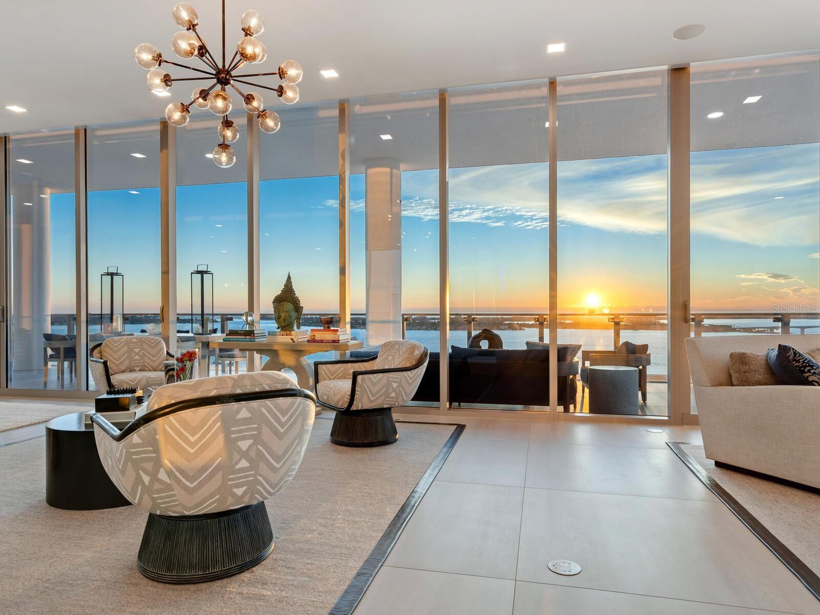 The pinnacle of ultra-luxury living in one of the highest waterfront residences on the Gulf Coast, EPOCH 17 is a full-floor masterpiece of architecture and design with spectacular vistas extending over Sarasota Bay to the Gulf of Mexico and in every direction across the city skyline. Sprawling over 5855 square feet with a magnificent owners’ wing and three luxurious en suite guest suites, this residence integrates exceptional comfort, cutting-edge technology, and haute design elements in every feature for an unequivocally lavish lifestyle. Beyond the impressive appointments of the interior, floor-to-ceiling impact glass walls and three enormous private terraces showcase 360-degree views and modern elegance of this chic new construction building.
With private elevator access, a spacious foyer leads to the great room that spans the width of the building to showcase stunning, unobstructed sky-high views through a full wall of floor-to-ceiling glass that opens seamlessly to the immense wraparound terrace. Soaring 12’ ceilings and an open floor plan add to the grand scale of the central living spaces, with distinctive zones arranged to preserve a sense of intimacy. Adjacent to the great room and ideal for large-scale entertaining, the open dining area enjoys direct access to the terrace and additional seating both outdoors and at the oversized dual-height kitchen island. The gourmet kitchen extends to a separate butler's pantry and features bespoke Italian cabinetry by Cucine Ricci, a 3’ Galley sink, expansive storage, quartzite and Caesarstone surfaces, and highest-end Gaggenau appliances that include six-burner gas range, double wall ovens, side-by-side refrigerator and freezer, and wine refrigerator and ice maker in the dedicated bar area.
With spectacular west-facing vistas, the owners’ suite is a luxury retreat beyond par. The massive bedroom encompasses a separate seating area and direct access to the bayfront terrace with additional private lounge space. Beyond the sleeping area, an enormous dressing room and additional walk-in closet are indulgent companions to the oversized bathroom with a huge walk-in shower, soaker tub, double vanities with seating, and separate water closet.
Decorative elements include Phillip Jeffries wall coverings, exquisite lacquering, Robern vanity installations, custom California Closets systems, and more. Premium technological integrations include Lutron automated shades, lighting control, and temperature control; A/V technology, sound system with built-in speakers in every room and bathroom; built-in WiFi and repeater system; multi-zone air conditioning; whole home water purification and reverse osmosis system for the kitchen. Two separate in-home laundry facilities, a dedicated guest beverage station, multiple storage rooms, and a private enclosed 3-car garage enhance the conveniences.
EPOCH was conceived to accommodate the highest level of luxury living, designed with meticulous detail and striking features that celebrate the renowned mid-century modern style of the Sarasota School of Architecture. The 23 exclusive residences enjoy world-class amenities, personalized services, and enhanced security. Desirably located on the shoreline of Sarasota Bay and within steps of the city’s cosmopolitan core, EPOCH marries contemporary elegance and unrivaled quality for the height of luxury living on the Gulf Coast. Bedroom Closet Type: Walk-in Closet (Primary Bedroom).