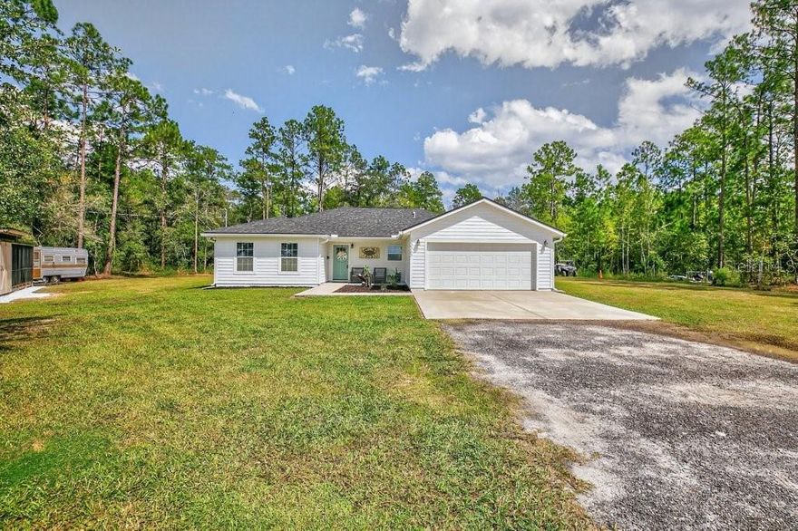 This 4-bedroom, 2-bathroom home has been meticulously maintained. Built in 2022, it sits on just over 1 acre of open rural land (no HOA) in sought-after St. Johns County, known for its top-rated school district. The thoughtful open floor plan places three bedrooms on one side of the home with the primary suite on the other for added privacy. The interior features luxury vinyl plank flooring throughout for both style and durability, and the kitchen is upgraded with granite countertops, soft-close cabinetry, and plenty of workspace, all highlighted by finishes that give the home a warm coastal farmhouse feel. A double car garage offers convenient parking and storage, while a detached workshop provides the perfect place to bring your projects to life with endless possibilities for hobbies. The spacious lot offers room for chickens, a garden, or outdoor exploring. The property operates on its own well and septic system, giving you added independence and fewer monthly utility bills. Directly across the street, a lush sod farm provides the kind of hard-to-find long-range views that make this property truly special. The location is convenient—just around 30 minutes to the beach and St. Augustine, with easy access to I-95. The nearby town of Hastings hosts numerous festivals, a new private school, shops, restaurants, and a beautiful new library currently under construction. This property combines the freedom of rural living with the convenience of nearby amenities—a rare find in today’s market.