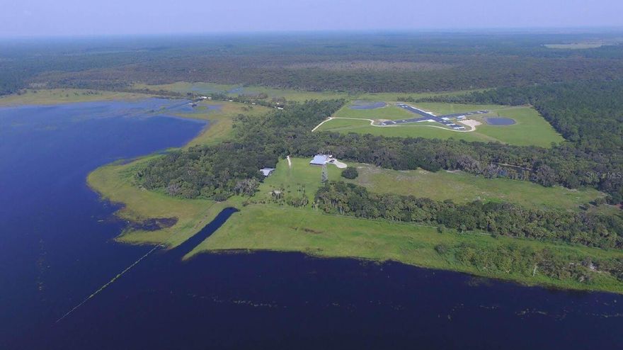 Pilots, ranchers, fisherman, equestrians. Land your seaplane in Lake Harney, taxi to your door and enjoy the quiet life in the heart of Central Florida. Located just 40 minutes to downtown Orlando, beaches or the attractions. This is your country home. Lake Harney is one of the largest lakes in Central Florida. A 7 story lookout tower allows multiple lake views. Lake Harney has plenty to offer, including skiing, world class bass fishing, water fowl hunting, and boating to Jacksonville along the scenic St. Johns River. With approximately 1400 feet of lakeshore, this ranch provides multiple water sport options. Land your helicopter on the helipad and pull right on in to the 2100 sq. ft. hangar attached to the rear of the home. The hangar is rated for 200 mile per hour winds. The main house is a handsome Florida lodge with a full kitchen, three bedrooms and two baths. The interior of the home has lots of wood and barn doors. On the backside of the hangar is a guest suite with a private entrance and kitchenette. Guests will enjoy privacy on the wrap around porch. The horse barn and shop offer 7 stalls for the horses and a nice large shop for your equipment. There is also a beautiful detached 1 bdr 1 bath bunkhouse. Includes E parcel 030400000050 ;Water: City