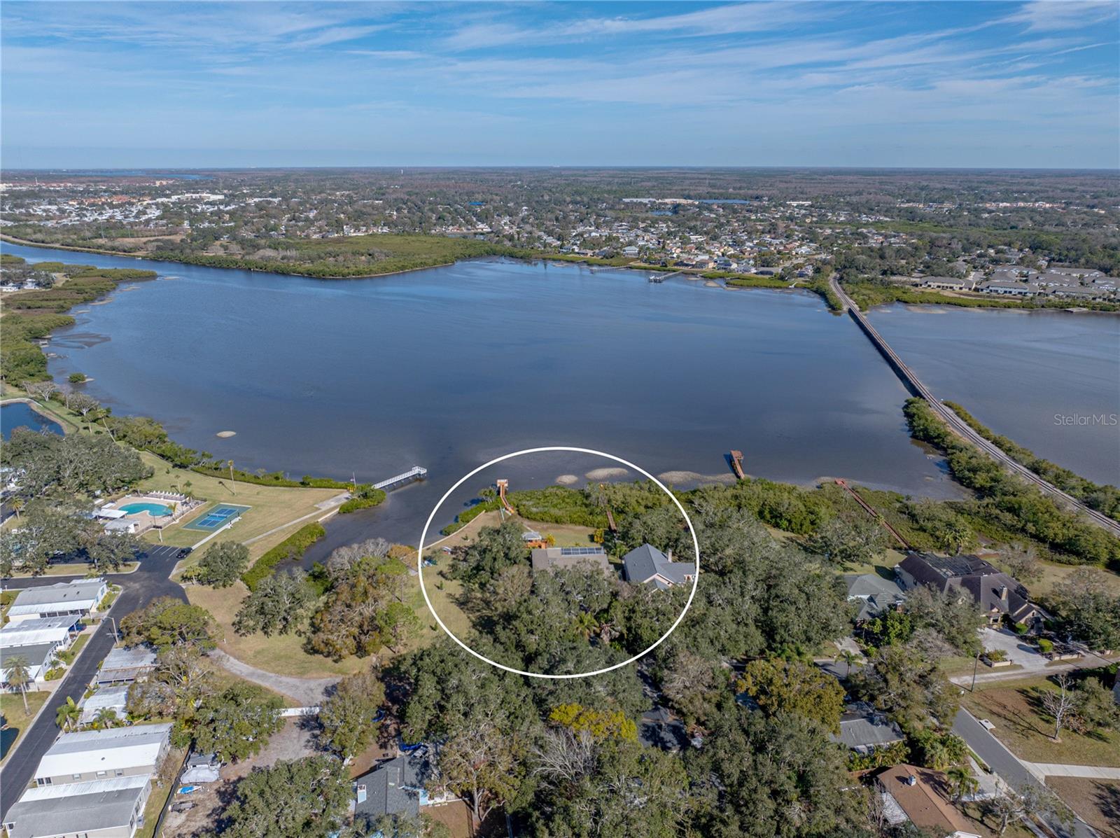 Welcome to your very own slice of paradise in charming Safety Harbor! This exceptional 4-bedroom, 3 and a half-bathroom waterfront estate offers an unparalleled lifestyle with 250 feet of direct frontage on the sparkling waters of Old Tampa Bay. Nestled on a beautifully landscaped lot, this home boasts incredible outdoor living, luxurious amenities, ultra-high-end finishes, and space for the whole family—including a private studio-style in-law suite with a full kitchen on the lower level. Stepping through the large double doors, you’ll walk inside to a lovely two story foyer with soaring ceilings. The in-law suite is straight ahead but the rest of the home is just up the stairs. Style starts from the moment you walk in with polished metal handrails and a glass banister on the stairs. Large slotted wooden doors give you a coastal modern feel along with the colors and openness of the space. Once you climb the steps, you’ll find spacious, light-filled living areas designed to capture water views from the wall-to-wall windows. The open-concept floorplan flows seamlessly, perfect for entertaining or relaxing in style. The kitchen is in a single word, immaculate. Stone counters, modern cabinetry, and designer pendant light fixtures hang over the oversized island. The backsplash is a breathtaking display of interlocking metal tiles, which goes well with the modern cabinetry. High-end stainless Bosch appliances provide both style and function to the space. The primary suite is a nearly 700 sq ft private oasis located through a pair of double doors off of the living room. Elegant high ceilings, upgraded fixtures, large picture windows overlooking the water, and a sitting area highlight the bedroom itself which has a stunning sense of tranquility. But with a step through into the bathroom, you’re in a spa-like experience that is unrivaled. Stone counters, a modern soaking tub, and an oversized walk-in shower. That alone would take your breath away but we’re not done. On the other side of the bathroom is the walk-in closet complete with wall-to-wall, floor-to-ceiling custom shelving, an island/dresser with display drawers, and two windows for added natural light. Rounding out the main level are two more well-appointed bedrooms that also do not skimp on style and share a jack-and-jill style bathroom. The bedrooms are on a split plan to allow everyone privacy and quiet at the end of the day. You will find a half bath and laundry room located on this level as well. Head back downstairs and enjoy the screened-in pool and spa, where a large pavered lanai with multiple seating areas invites you to unwind and soak up the serenity. Whether you’re hosting a sunset gathering or enjoying a quiet morning coffee, the expansive gazebo overlooking the bay is the perfect backdrop. For the boating and fishing enthusiast, the private dock includes a water supply and 4-point mooring—ideal for casting a line or it can be modified for launching your kayak. And with more than five garage spaces, there’s plenty of room for vehicles, water toys, conversion to the ultimate mancave, craft room, or even a workshop. All this in a quiet, desirable area just minutes from downtown Safety Harbor, Philippe Park, Clearwater, and world-class dining and amenities. Don’t miss this rare opportunity to own a one-of-a-kind waterfront property where every day feels like a vacation.