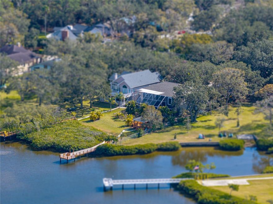 Your dream home awaits in the heart of coveted Safety Harbor! This breathtaking waterfront estate offers the perfect blend of luxury, serenity, and modern living, with 4 bedrooms, 3.5 bathrooms, and an unbeatable 250 feet of frontage along the shimmering waters of Old Tampa Bay.

Set on a lushly landscaped lot, this home is a masterpiece of design and functionality. From the moment you step through the grand double doors, you’re greeted by a soaring two-story foyer and a striking coastal-modern aesthetic. Sleek polished metal handrails and a glass banister set the tone for the impeccable style that flows throughout the home.

Upstairs, the open-concept living spaces are bathed in natural light, thanks to floor-to-ceiling windows that frame jaw-dropping water views. The kitchen is a chef’s dream—boasting stone countertops, an oversized island, designer pendant lighting, high-end Bosch stainless appliances, and a dazzling backsplash of interlocking metal tiles. Here, every detail has been curated to impress.

The nearly 700-square-foot primary suite is a retreat like no other, offering panoramic water views, a tranquil sitting area, and extra high ceilings. The spa-inspired en-suite bath features a modern soaking tub, an oversized walk-in shower, and dual vanities with stone counters. Beyond the bathroom, a show-stopping walk-in closet awaits, complete with custom shelving, a central island with display drawers, and even natural light from two windows.

Two additional bedrooms on the main level are equally stylish and share a Jack-and-Jill bath, while a separate half bath and laundry room add convenience. Downstairs, the private in-law suite is a standout feature, complete with its own kitchen, living space, and direct access to the outdoors—perfect for extended family or guests.

Step outside, and you’ll discover your personal paradise. A screened-in pool and spa with a sprawling pavered lanai offer multiple seating areas for relaxation or entertaining. The gazebo overlooking the bay creates an idyllic spot for morning coffee or sunset cocktails, while the private dock with water access is a dream for boaters and anglers alike. With over five garage spaces, there’s room for all your toys—whether it’s a boat, jet skis, or even a workshop.

Located in a quiet, sought-after neighborhood minutes from downtown Safety Harbor, Philippe Park, and Clearwater’s world-class beaches and dining, this estate is more than a home—it’s a lifestyle. Don’t miss the chance to make every day feel like a vacation in this one-of-a-kind waterfront gem!