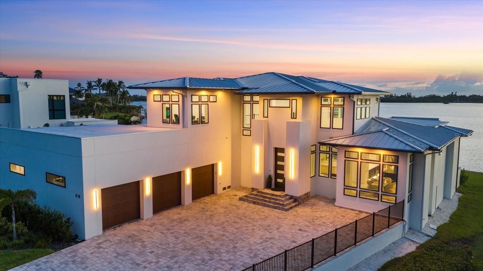 Commanding over half an acre with 116 feet of pristine frontage on Little Sarasota Bay, this brand-new custom estate captures the essence of coastal luxury. From the moment you arrive, you are greeted by sweeping water views and spectacular Casey Key sunsets, setting the stage for an extraordinary lifestyle.
Designed for the boating connoisseur, the property boasts a new dock with water, electric, a 20,000 lb boat lift, and direct bay access—no bridges to the Gulf.
For the automotive enthusiast, a 1,400 sq. ft. climate-controlled garage with 14-ft ceilings, professional-grade car lifts, epoxy floors, perfect showcase for your collection.
Inside, the home flows across two levels with 3 ensuite bedrooms, 4.5 baths, an office, and a dramatic 24-ft coffered ceiling living room. The chef’s kitchen is an entertainer’s dream, featuring two massive islands, bespoke Yoder cabinetry with stainless steel inlays, and Bertazzoni appliances imported from Italy.
The primary suite is a private retreat with a spa-inspired bath, custom walnut cabinetry, dual shower with body jets, and a grand walk-in closet. Each guest suite offers its own spa-like bath.
Constructed with poured concrete walls coated in Styrofoam and stucco for superior soundproofing, this residence offers both durability and comfort. Additional features include two central A/C systems, top-of-the-line sound and camera security, hurricane-resistant 14-ft ASL garage door, computerized pool controls, custom floors, bar area, 1,000-gallon LP tank, and UV-protected screens.
Outdoor living is nothing short of exceptional, a custom waterfall pool (oriented east–west for optimal sun), spa, fire bowls, LED-lit fountain, and a full pool bath create the ultimate entertaining environment with an unforgettable bayfront backdrop. The new fenced and paved driveway ensures privacy and curb appeal, while the turnkey condition makes it move-in ready.
Located just minutes from Casey Key, Siesta Key Beach, and the A+ rated Pine View School, this estate is more than a home, it’s a statement of refined living, where boating, entertaining, and coastal elegance converge.