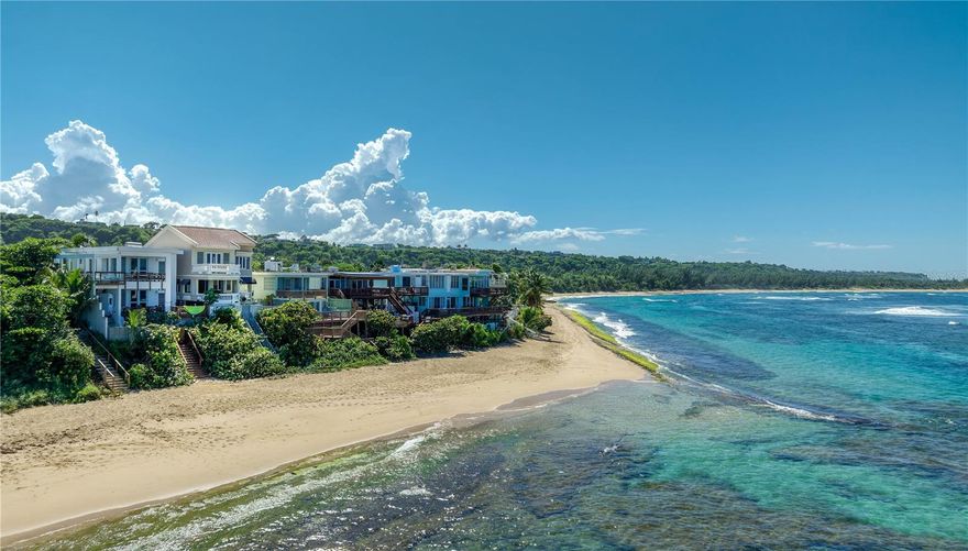 Set directly above the turquoise waters of Shacks Beach, this five-bedroom, three-and-a-half-bath residence embodies the essence of refined coastal living. Blending timeless Caribbean architecture with modern amenities, it offers sweeping ocean views and two expansive terraces that capture the rhythm of the waves. The main home features three bedrooms, two full bathrooms, and a powder room. The primary suite, located on the top floor, enjoys panoramic ocean vistas, a private balcony, a generous walk-in closet, and direct access to a beautifully appointed den lined with custom wood cabinetry with the sea as your backdrop. The main living floor offers two spacious guest bedrooms, a full bath, and a powder room. The open kitchen and great room flow naturally to the terraces, inviting indoor-outdoor living at its best. A private staircase leads directly down to the sand, creating an effortless connection to one of Puerto Rico’s most beautiful beaches. On the lower level, a fully independent guest apartment includes two comfortable bedrooms, a bathroom, a full kitchen, and living-dining area, ideal for visitors or private hosting. This level also houses the temperature-controlled wine cellar and access to the two-car garage. Sustainable living is seamlessly integrated with solar panels and Tesla Powerwall batteries, ensuring energy efficiency and peace of mind. Surrounded by lush tropical vegetation, the property maintains a serene sense of privacy and natural beauty that make Isabela’s coast so sought after. From sunrise coffee on the terrace to evenings framed by ocean breezes, this Shacks Beach residence captures the quiet luxury of life lived by the sea. Located along Puerto Rico’s northwest coast, Shacks Beach is known for its pristine reefs, golden sand, and year-round breezes. A haven for divers, kite-surfers, and beach lovers alike, the area retains a quiet exclusivity while being minutes from the restaurants, boutique hotels, and art-filled streets of Isabela and Aguadilla.