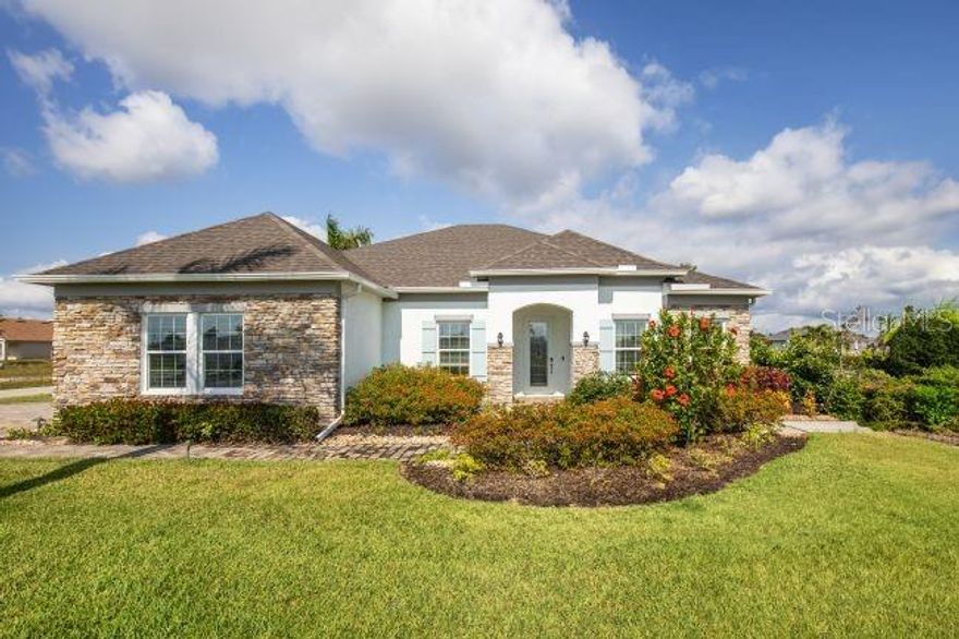 Pre-Construction. To be built. The Venice home design in Mount Plymouth Green is set within an intimate cul-de-sac community just 8.5 miles from downtown Mt. Dora, where oversized homesites provide the extra space so many are seeking. This setting captures small-town charm while keeping everyday conveniences close at hand, creating a seamless blend of comfort and accessibility. Paved walking paths and open green spaces enhance the neighborhood, with inviting places to relax and enjoy the outdoors.

The Venice is a striking residence that blends modern elegance with everyday functionality, highlighted by high-end upgrades throughout and a private guest suite designed for comfort and distinction. From the moment you arrive, the stone-accent exterior, driveway and path brick pavers, 8-foot glass front door, covered front porch, 3-car side-facing garage, and architectural shingles create a memorable first impression. Step through the tray ceiling foyer into a thoughtfully designed interior featuring 9-foot ceilings, crown molding, cordless blinds, and elegant ceramic tile flooring throughout.
At the heart of the home, the spacious great room is ideal for both relaxing and entertaining. Just off this space, a den with double French doors with sidelights, a tray ceiling, and an additional window provides flexibility for a home office, media room, or quiet retreat. The gourmet kitchen is designed to impress, showcasing a large island with quartz countertops, a walk-in pantry, tile backsplash, and a full suite of stainless steel appliances, including a wall oven, cooktop, and ENERGY STAR side-by-side refrigerator. The dining area flows effortlessly from the kitchen and opens through French doors to a covered lanai, extending the living space outdoors.
The owner’s suite serves as a peaceful retreat, privately positioned while still conveniently connected to the main living areas. It features a spa-inspired bath with a walk-in tiled shower, a separate soaking tub, quartz dual vanities, and refined finishes throughout. Three generously sized secondary bedrooms provide flexibility for guests, hobbies, or additional workspace. The private guest suite stands out for its discreet placement, creating a comfortable and secluded space visitors will appreciate.
Additional highlights include a laundry room with wall cabinets for added storage, meticulously maintained landscaping with irrigation, and an oversized homesite that provides plenty of room to spread out and enjoy. Smart features such as Deako switches, keyless entry, and impact windows enhance ease, security, and everyday living. The Venice brings together luxury and livability in a design that elevates how you live, all backed by a full builder warranty for added peace of mind.