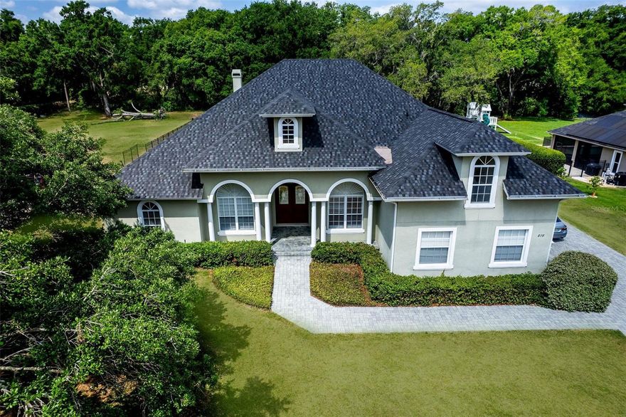 One or more photo(s) has been virtually staged. JUST REDUCED! 1 FULL ACRE in Cardinal Pointe, an exclusive gated community of custom homes where luxury, space, and tranquility seamlessly blend. This stately residence is gracefully landscaped, offering the ultimate privacy and curb appeal. A long, elegant pavered driveway welcomes you with majestic oak trees and a charming front porch swing, setting the tone for the warm sophistication found within.
Step through grand double doors into soaring ceilings that create an open, airy ambiance. Every detail has been thoughtfully curated—from plantation shutters and tray ceilings to extra-tall baseboards and refined crown molding, each element adds timeless elegance to every room. Newly installed Italian porcelain tile, known for its durability and versatility, flows throughout most of the main living areas, complementing any interior design style.
The formal living room/den and dining area are ideal for entertaining, while the heart of the home—the gourmet, fully remodeled kitchen—caters to the culinary connoisseur. Outfitted with top-tier appliances, custom soft-close cabinetry, a striking porcelain backsplash, quartz countertops, a deep cast iron sink, and a spacious center island, the RENOVATED kitchen blends form and function effortlessly. It opens seamlessly to the inviting family room, which in turn extends to the covered lanai, perfect for indoor-outdoor entertaining.
The Primary Suite is a true sanctuary, featuring plush new carpeting, dual walk-in closets, and a BRAND NEW spa-inspired en-suite with a luxurious soaking tub, walk-in shower, and dual vanities. Two additional oversized bedrooms share a well-appointed Jack and Jill bath, while a fourth bedroom—tucked away with access to a full bath and the lanai—offers a perfect guest suite or multigenerational option.
Upstairs, discover a massive bonus room with full bathroom—a versatile space ideal for a home theater, game room, private office, or even a fifth bedroom.
Outside, your personal oasis awaits. Step through glass doors to an expansive covered lanai featuring a sparkling pool and spa with tranquil water features, surrounded by ample space for lounging, entertaining, and soaking in the Florida sun. The generous backyard invites everything from gardening to outdoor play, all in total privacy.
Additional highlights include a NEW ROOF (Nov 2024) with a 25-year transferable Gold warranty, fresh interior paint, newer A/C systems, and updated lighting fixtures throughout much of the home.
Located just minutes from Sanford’s vibrant downtown, with easy access to lakes, parks, major highways, shopping, dining, and top-rated Seminole County schools, this home offers a rare combination of luxury, lifestyle, and convenience.