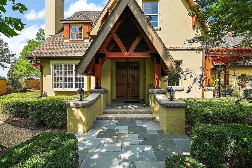 STORYBOOK ELEGANCE MEETS FLORIDA LIVING! Nestled in the quaint and scenic town of *Howey-in-the-Hills*, this stunning Tudor Revival residence exudes timeless charm and modern functionality. With 5 bedrooms, 3.5 baths, and distinctive architectural details, this home offers space, style, and a seamless blend of rustic elegance and everyday comfort. A picturesque exterior welcomes you with steep gables, wood trimmed doorways, a warm stucco finish, and stone-accented walkways. It's a nod to its European-inspired design. Inside, the grand great room captivates you with a soaring vaulted ceiling clad in tongue-and-groove wood, rich wood look flooring, and a floor-to-ceiling stone fireplace framed by arched windows that fill the space with natural light. At the heart of the home, a charm-filled kitchen showcases custom green beadboard cabinetry, coordinated with copper look hardware, warm wood accents, stainless steel appliances, two full refrigerator/freezers side by side, pendant lighting, and a central granite-topped cooking island with open shelving. The 8 burner cooktop plus wet bar complete this warm and inviting kitchen. This beautiful and functional space flows into open living and dining areas, ideal for gatherings and everyday living.Unique to the home are two staircases that provide flexible access to the upper levels, where you’ll find a thoughtfully designed in-law suite on one side—perfect for multi-generational living or guests seeking privacy. And the other staircase leading you to the other 3 bedrooms and full bath. Additionally, another very unique feature are two secret doors with one leading to the spacious basement. Need storage or something more? The basement offers incredible potential—ideal for extra storage, a wine cellar, man cave, billiard room or even a safe room. Step outside to a private, screened-in pool area, a true Florida oasis. The freeform pool with a built-in spa is surrounded by natural stone decking, lush tropical landscaping, and a covered patio for dining and lounging. The primary bedroom with tongue and groove wood valuted ceiling is a peaceful retreat and has an en suite spa like bathroom with tons of character. Whether you’re hosting, relaxing, or creating lifelong memories, this one-of-a-kind residence delivers character, comfort, and the very best of the Florida lifestyle. Words can not describe this home-it will be a treat to live in one of the most distinctive homes in Lake County. This standout property is a must see!