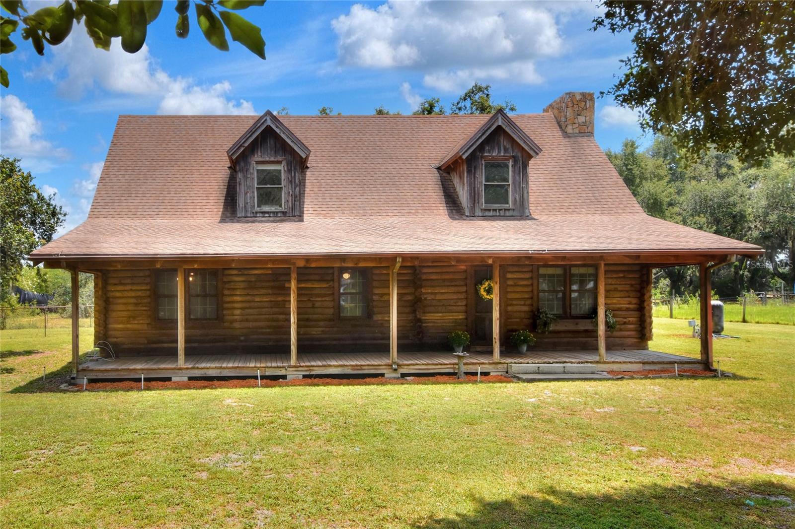 One or more photo(s) has been virtually staged. Rustic Charm Meets Country Living- Welcome to your dream retreat! This beautifully crafted 3-Bedroom, 2-Bath Solid Pine log cabin sits on a fully fenced 4.40-acre parcel surrounded by majestic oak trees, offering privacy, tranquility, and space for your animals horses or cows! Step into the full-length front porch and into a warm, inviting interior highlighted by a dramatic floor to ceiling stone fireplace. The heart of the home features spacious living area, double kitchen pantries, and an extra shower in the laundry room for added convenience. The Primary suite is located upstairs in a large open loft, boasting double walk-in closets and views of the serene landscape. Enjoy the peace and quiet from your covered back porch, perfect for morning coffee or evening gatherings. Additional features Inside Workshop, Built-In indoor kennels ideal for pet lovers, Rustic character throughout with log walls, natural wood finishes, and country charm. Whether you are looking for a private homestead, mini farm, or peaceful escape, this is a one-of-a-kind property offers endless possibilities in a highly desirable North Lakeland location. NO HOA! Call today!