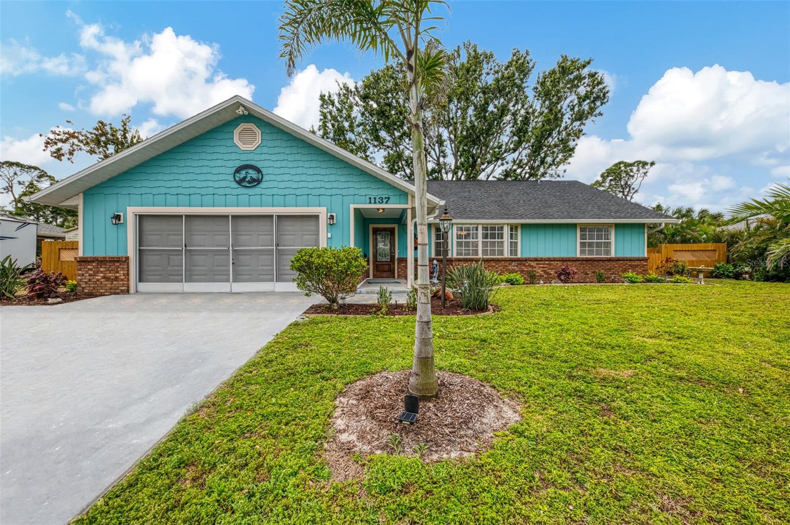 Not like the rest! This charming 3-bedroom, 2-bath, 2-car garage custom home is full of character, thoughtful design, and fantastic upgrades. With nearly 2,000 sq. ft. under air, an air-conditioned bonus room above the garage, and a fenced yard, this home offers style, space, and functionality in a prime location. Step onto the inviting covered front porch, where the peaceful sound of a private fish pond with a fountain is surrounded by lush greenery and flowing shrubs. A gorgeous leaded glass front door sets the stage for what’s inside. Soaring tall, angular ceilings and an expansive layout make this home feel open and welcoming. The huge 10x18 kitchen features solid wood cabinets with pull-out drawers, a tiled backsplash, LED lighting, and ample counter space, including a cozy breakfast bar overlooking the dining area. The kitchen comes complete with stainless steel appliances and a washer and dryer! The floor plan flows effortlessly into a 27-ft. living room with a picturesque bay window and a 27-ft. family room with a wood-burning fireplace—perfect for creating a warm and inviting atmosphere. French doors lead to a spacious tiled patio, offering the perfect outdoor retreat. The primary suite is a true escape, boasting a 13x19 layout, a large walk-in closet, French doors to the patio, and a private ensuite with a granite counter vanity and a tiled walk-in shower. On the opposite side of the home, pocket doors provide additional privacy for the guest rooms. The second and third bedrooms (12x12 each) include ceiling fans, with the third bedroom featuring mirrored closet doors and French doors leading to the family room. The guest bathroom is designed for relaxation, offering a granite counter vanity and a deep jetted tub with a shower. This home is filled with impressive updates, including a new roof, newer A/C, and a solar hot water heater, helping to keep energy costs low. Additional thoughtful features include keyless entry, a Rainbird irrigation system, a top-of-the-line water softener, and irrigation designed specifically for hanging flowers in the front yard. A hookup for a hot tub is already in place, while the leaf guard gutters and backyard storage shed add even more convenience. The garage is screened in, and an extra parking pad provides plenty of space for guests or recreational vehicles. Located in highly desirable South Venice, this home offers optional membership to the South Venice Ferry, giving access to a private beach, boat ramp, and kayak launch. Shamrock Park is just minutes away, offering tennis courts, basketball, nature trails, and a playground. With downtown Venice, Venice Beach, shopping, and dining nearby, this home offers a perfect blend of privacy, upgrades, and prime location. Don’t miss out on this one-of-a-kind property!