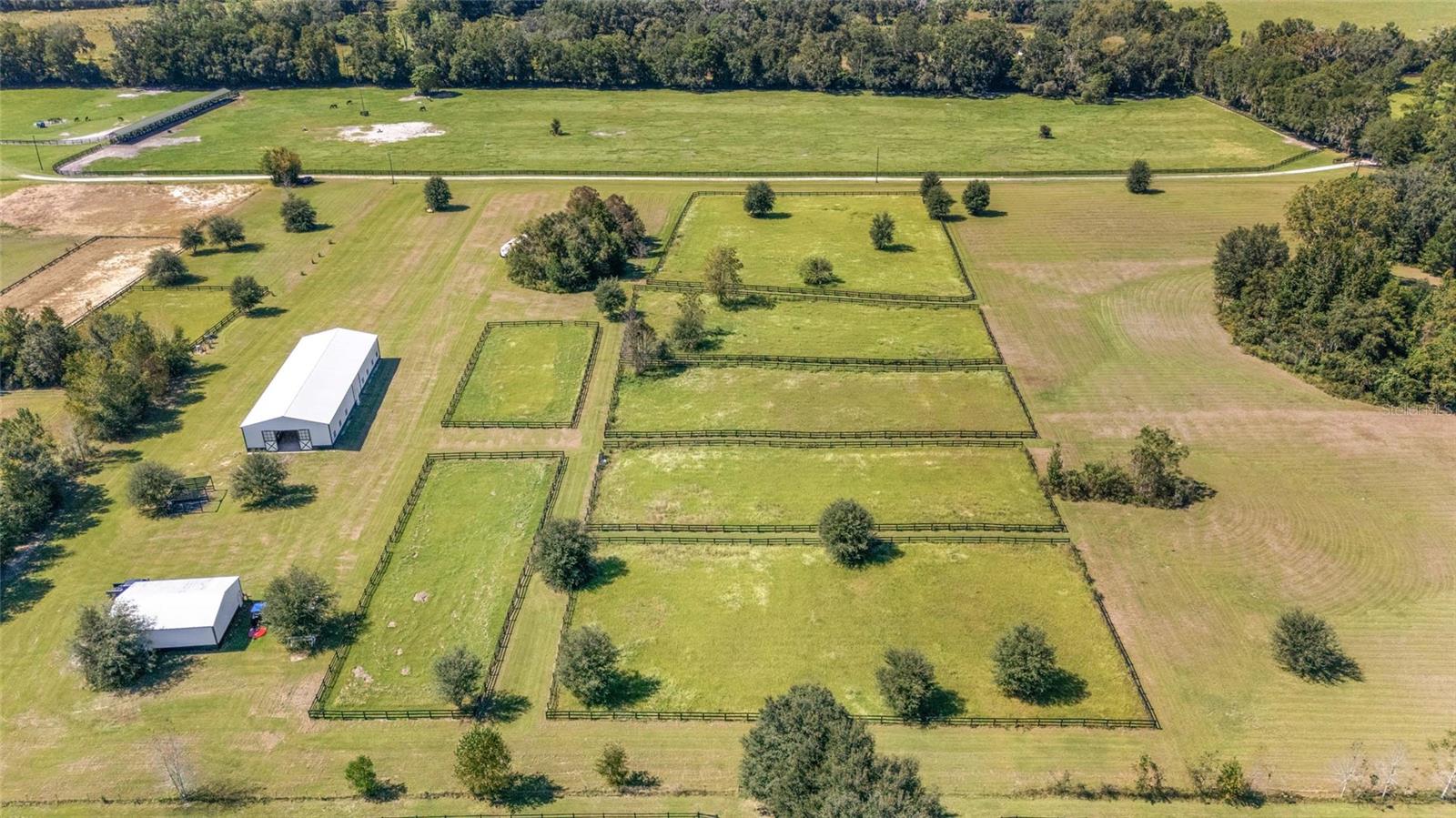 Turnkey 20-Acre Horse Farm in Prime NW Ocala Location. Situated on a quiet, picturesque road surrounded by premier horse farms, this exceptional 20-acre equestrian property is a rare find in Ocala’s highly sought-after northwest corridor. Just 2 minutes from HITS and only 10 minutes to WEC, this turnkey farm is perfectly located for the serious equestrian. The newly constructed center-aisle barn is thoughtfully designed and impeccably outfitted with 12 oversized stalls featuring European fronts, automatic waterers, and comfort stall mat system for ultimate equine comfort. The barn also includes two large grooming stalls, a climate-controlled tack room with custom cabinetry, and a spacious feed room complete with built in storage. A 1/2 bath with laundry adds convenience, while two outdoor wash racks, a water filtration system, and an large three-bay equipment garage/workshop/storage round out the amenities. Additional equine facilities include eight fenced paddocks, each with water and separated by safe grass 'hacking' lanes. Enjoy an irrigated dressage arena, a large grass jump field, and plenty of room to school on the property. There’s even an RV hookup with septic for added flexibility. A truly move-in-ready facility that blends high functionality with thoughtful design—don’t miss this rare opportunity in one of Ocala’s premier equestrian areas. The property is being sold with tractor, zero-turn mowever, Jumps, etc..... Property is ready for it's new owners for the 2025/2026 Horse Show Season.