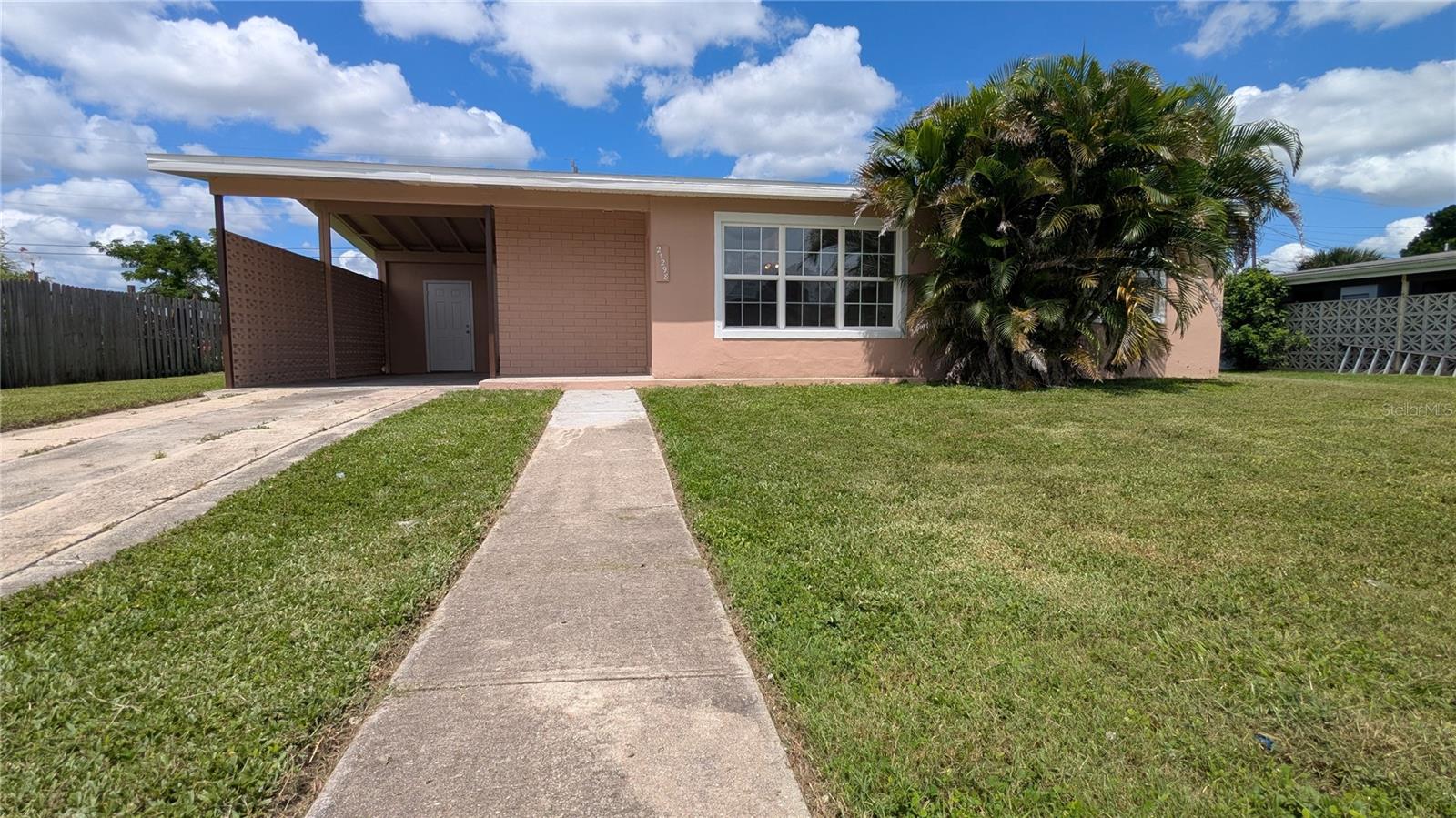 Your potential next home awaits. This spacious two bedroom one bath home has a split floor plan with open concept kitchen, dining and living room. Bonus enclosed Lanai. Nice size kitchen with lots of cabinet space for storage. Home is tiled throughout for easy maintenance. Laundry room located inside just off the kitchen. Outside you will a large carport with storage room. The carport has access an entry to the home for ease of use. Come see this centrally located spacious home today.