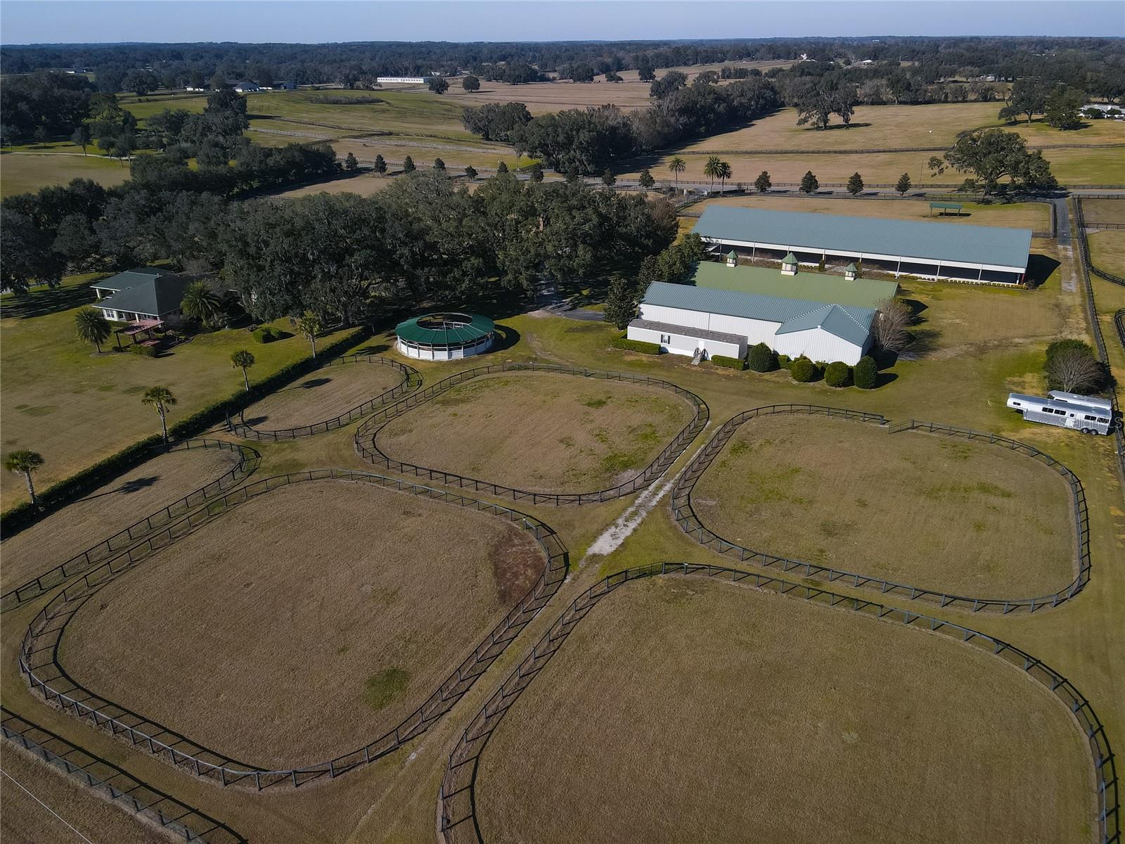 Located in the heart of NW Ocala's ''Golden Corridor'' is this extraordinary 26+ acre horse farm, situated next door to the beautiful Longwood Farm. This impeccably maintained farm is home to an 8-stall center aisle barn with kitchen, bath, tack room, washer and dryer, and multiple wash racks with hot water. There is also a covered arena, a second arena, and a new covered Eurosizer. A huge storage building provides an additional 8 stalls, bathroom, washer and dryer, tack room, equipment/feed/hay storage, and a fully equipped 1 BR apartment, perfect for ranch hands, or guests. A single-wide manufactured home is also included. The lush pastures are all lined by beautifully maintained board fencing. The beautifully-appointed home is surrounded by centuries-old graceful oaks, and has many fantastic amenities including large island kitchen, wood cabinets, walk-in pantry, and granite counters. A 2019 renovation included the addition of a beautiful second master bedroom suite with its own washer and dryer. The home also boasts an over-sized laundry room, magnificent fireplace, and lovely covered patio overlooking the rolling pastures beyond.