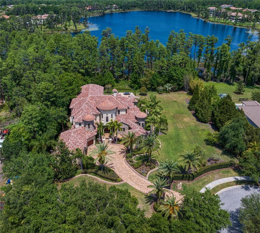 Welcome to this breathtaking gated estate in Ladera on Lake Merry Water. Custom designed and built with the finest materials and premium finishes, this spectacular residence offers unparalleled craftsmanship and elegance. Situated on an expansive parcel — over an acre with the inclusion of the adjoining lot — the setting is truly one-of-a-kind. Featuring 6,783 square feet, this exceptional home offers 5 bedrooms, 5 Full bathrooms, 2 Half Bathrooms, a private home office, an elevator and a spacious bonus/game room — everything you need to truly love where you live. From the moment you arrive, you’ll be captivated by the beautifully landscaped grounds and the private gated entry, offering the ultimate in security and privacy. Upon arrival, be welcomed into a world of timeless luxury, where rich wood-paneled walls, a soaring double-height foyer, and a sweeping stair case welcome you.  The formal living room captivates with floor-to-ceiling windows, a custom gas fireplace adorned with an exquisite mantle, and a wood-beamed ceiling that exudes refined sophistication and warmth. The formal dining room is a showpiece, highlighted by a custom brick ceiling, a built-in buffet, and a beautifully appointed adjoining wine room. The kitchen is a chef’s masterpiece, outfitted with the finest professional-grade appliances, including Two Sub-Zero refrigerators, Two Sub-Zero freezers, Two dishwashers, a built-in steamer, an additional prep sink, and a professional Wolf gas cooktop featuring six burners, a grill, a griddle,  and double ovens. This extraordinary culinary space is complete with a custom marble backsplash, under- and over-cabinet lighting, intricate crown and rope detailing on the cabinetry, a butler’s pantry, a built-in desk area, a reverse osmosis water system, and a large walk-in custom pantry.  The first-floor owner's suite is a luxurious sanctuary, featuring rich hickory hardwood floors, a tray ceiling, a private sitting room, and two expansive walk-in closets. The spa-inspired owner's bathroom is equally impressive, offering dual vanities plus a separate sit-down vanity, a jetted soaking tub, an oversized walk-in shower with four shower heads and multiple body sprays, a towel warmer, a bidet, and a large linen closet — every element thoughtfully designed for ultimate comfort and indulgence. The spectacular family room features a striking beamed ceiling, a custom built-in entertainment center, and two sets of sliding glass doors that recess, seamlessly blending indoor and outdoor living while offering unobstructed views of the pool and lake. Upstairs, you’ll find three private bedroom suites, a spacious bonus room, and a home theater that can easily serve as a fifth bedroom. The upstairs bonus room is perfect for entertaining, showcasing custom-designed built-in cabinetry, a mini kitchen complete with a dishwasher, copper sink, and refrigerator, plus two sets of pocketing sliders that open fully to the expansive terrace — perfect for seamless indoor-outdoor gatherings. The outdoor living spaces are truly extraordinary, highlighted by a resort-style pool and spa, an expansive lanai, and multiple seating and lounge areas designed for relaxation and entertainment. The outdoor kitchen , features an Al Fresco grill with a smoker, a refrigerator, and an island with bar seating. Whether hosting intimate gatherings or grand celebrations, this exceptional estate offers endless opportunities for unforgettable entertaining.