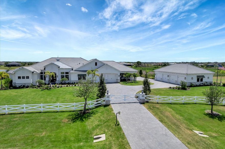 Welcome to 3574 Recurve Circle, an extraordinary opportunity to own a custom-built 2023 Modern Coastal Retreat nestled in the exclusive gated community of Hampton Lakes in East Sarasota. This remarkably gated 4-bedroom, 4.5-bathroom estate home with private pool spans 8.68 acres of serene countryside curating the ideal balance of sophistication, privacy, and peaceful Florida living. Built with meticulous attention to detail, this home is move-in ready, eliminating the stress and extended timelines often associated with new construction. From the moment you pass through the private gated entry, you’re greeted by a long-paved driveway lined with manicured landscaping and framed by timeless architectural lines that immediately set a tone of refined elegance. The setting is enhanced by a tranquil pond, providing a picturesque backdrop for sunrises, sunsets, and everyday relaxation. Inside, soaring ceilings and expansive windows flood the interiors with natural light, LVP wide plank flooring adds timeless charm and easy maintenance . The layout flows effortlessly, showcasing luxurious designer details that strike the perfect balance between elegance and comfort. At the heart of the home, a gourmet chef’s kitchen stuns with a tiled counter-to-ceiling accent wall, dacor wide refrigerator, professional-grade 48" Dacor 6-burner smart gas range with 1.5 ovens and 2 wall ovens, a warming drawer, a built-in island microwave, Jenn Air built-in coffee station, farmhouse sink, U-Line icemaker, and a custom walk-in pantry. A sleek bar area bridges the kitchen and living room, making it perfect for entertaining. The spacious laundry room enhances functionality and style with Electrolux steam washer/dryer units, a GE Café refrigerator, and custom cabinetry. In the main living areas, a custom wood vaulted ceiling and 2 stone fireplaces create a cozy ambiance. The dining room features a one-of-a-kind wood-and-mirror accent wall, ideal for intimate dinners or large gatherings. There is a dedicated home office for work or creative pursuits. The primary suite is a peaceful private retreat with tranquil views of the surrounding landscape. The spacious bedroom is paired with a luxuriously appointed spa-style bathroom and a boutique styled custom walk-in closet and a dry bar. The additional three bedrooms are spacious, well-positioned for privacy, and each paired with access to beautifully finished bathrooms—perfect for family or guests. Step outside and experience a resort-style heated saltwater pool and spa, framed by panoramic screens and surrounded by lush landscaping. The fully equipped summer kitchen features a 36” Lynx built-in grill, stainless steel hood, beverage fridge, and sink—ideal for alfresco dining and entertaining under the Florida sun. Additional highlights include a chic powder bath, an attached 4-car garage with front and side entrances, and a detached 4-car garage—offering a total of 8 garage bays for car enthusiasts, RVs, boats, storage, or workshop space. The home is equipped with smart home automation, impact-rated windows and doors, and a 38 kw whole-house generator for your peace of mind year-round. This exceptional estate in Hampton Lakes invites you to live expansively and luxuriously in one of East Sarasota’s most coveted gated communities—just minutes from shopping, dining and medical services, making this the perfect location! Don’t miss your chance to tour this extraordinary lifestyle property—schedule your private showing today.