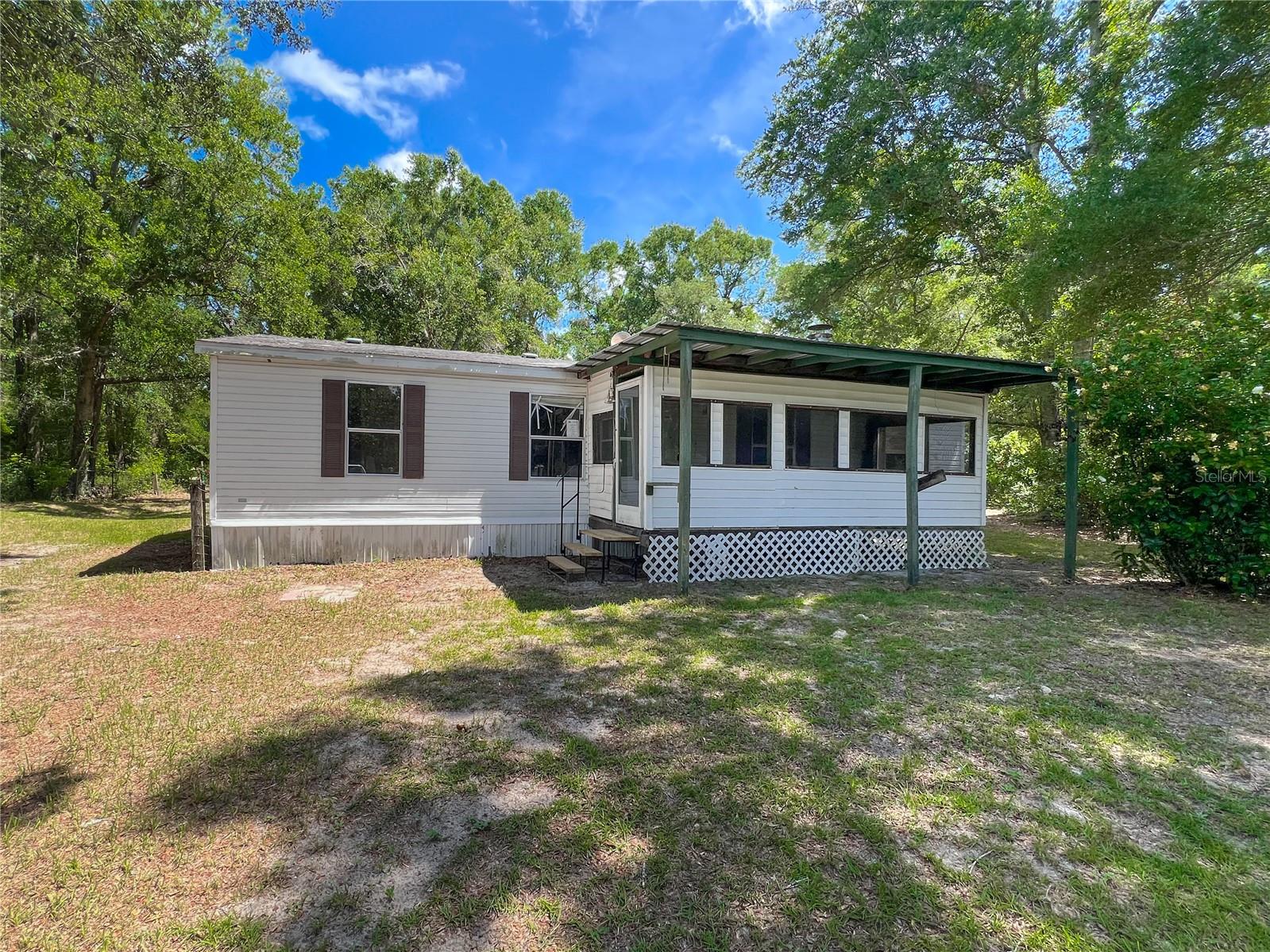 On the hunt for the perfect summer project? Look no further! This 3 bedroom/2 bath doublewide is ready to be renovated. It is situated on a mostly wooded 5-acre lot with paved road access. This 1995 home has 3 bedrooms, 2 full baths, a living room with built-in cabinets and fireplace plus front and rear porches. The primary suite has a separate sitting/office area and a walk-in closet. If a renovation project isn't on your to-do list, remove the existing home and place a new one. The property is located less than 5 minutes from the north entrance of Ichetucknee Springs State Park and less than 15 minutes from the charming town of Fort White.