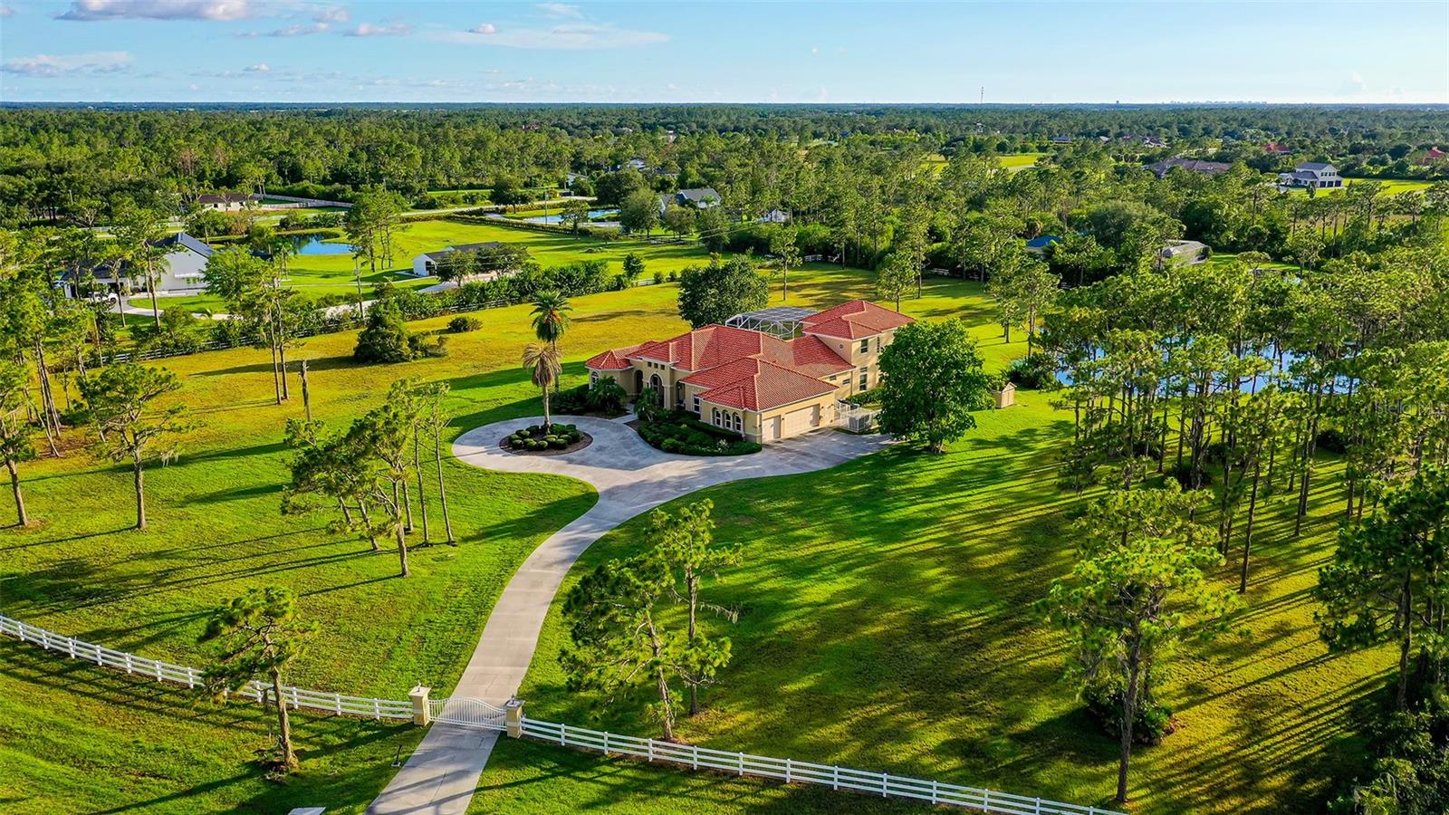 Welcome to Foxwood at Panther Ridge, an equine-friendly community where privacy meets a remarkable lifestyle. As the private gate opens to reveal this 6.73-acre estate, you'll be enchanted by the property's natural beauty. The Mediterranean-style custom pool home boasts top-tier, fortress-like construction and offers ample parking along the winding circular drive and in the three-car garage.
Step inside to be greeted by a breathtaking view of the expansive screened patio, which features a large heated swimming pool, spa, and outdoor kitchen equipped with a Lynx grill. This impeccably maintained home showcases a neutral palette, abundant natural light, 12-foot ceilings, a whole-house generator, and numerous custom details.
Ideal for entertaining, the spacious wet bar connects the living room and chef's kitchen, featuring a sink, generous counter space, cabinet storage, and a beverage cooler. The chef's kitchen is equipped with Subzero and GE appliances, as well as an oversized walk-in pantry. Adjacent to the living room is a generous home office designed with two custom-built workstations.
The palatial master suite occupies the front corner of the home, offering a bedroom with views of the backyard and pool, along with a luxurious bathroom that includes a large tub and an expansive shower with enhanced water pressure from both showerheads. The main level also features three additional bedrooms, three full bathrooms, and a spacious laundry room.
Upstairs, you'll find a bonus room and another bedroom with an en-suite bathroom, plus a second screened patio overlooking the pool. The outdoor space is equally impressive, featuring your own private stocked pond and a generous lot that offers a blank canvas for your dream oasis—whether that includes horse stables, a barn, or sports courts.
Panther Ridge boasts no CDD fees, a low HOA fee, and A-rated schools. Community amenities include a playground, basketball court, sports field, and park pavilion, along with an extensive network of trails for hikers and riders. Plus, you’re just minutes away from the vibrant shops and restaurants of Lakewood Ranch and UTC, surrounded by award-winning golf courses, and a short drive to the pristine beaches of Lido Key and Anna Maria Island.
This home perfectly combines exceptional features with a prime location—exactly what you’ve been searching for!