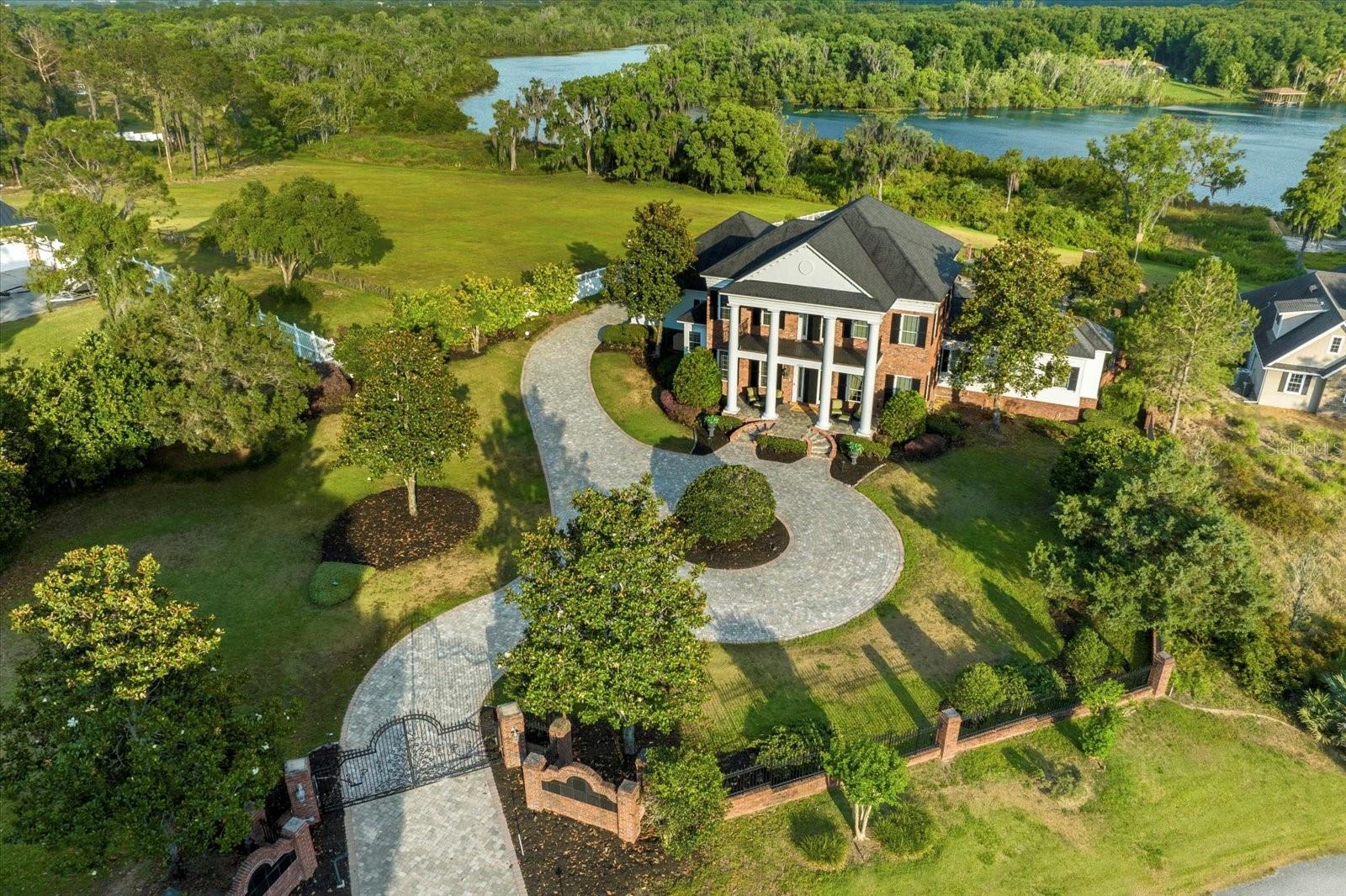 MOTIVATED SELLER! TURNKEY, FULLY FURNISHED WITH DESIGNER INTERIOR! Step into a world of unparalleled luxury in this exquisite lakefront estate on Horseshoe Lake, part of Central Florida’s renowned Harris Chain of Lakes. This fully furnished, turnkey masterpiece is adorned with Schonbek crystal chandeliers throughout, casting a radiant glow across the home’s refined living spaces. Large, striking pieces of art enhance the home’s elegance, adding a gallery-like sophistication to every room. From the moment you enter through the stately wrought iron gates, you’ll be captivated by the breathtaking designer interiors, soaring ceilings, intricate millwork, and elegant coffered details. The grand foyer opens to an expansive living area, where floor-to-ceiling windows bathe the space in natural light, highlighting the magnificent chandeliers and curated art pieces that create an atmosphere of refined luxury. The unmatched home theater is truly one of a kind—a cinematic experience unlike any other. Outfitted with a brand-new (2023) Epson 4K projector, premium surround sound, and 12 plush leather recliners, this state-of-the-art space cannot be found anywhere else. Whether you’re hosting a private screening or indulging in a solo movie night, this theater is a masterpiece in luxury entertainment. For fitness enthusiasts, this estate boasts a gym designed for professionals, featuring Nautilus chain-driven machines for a superior strength-training experience. This fully equipped, high-performance fitness space is built for those who demand the best in their workouts, offering commercial-grade equipment in the comfort of your own home. Whether you're focused on strength training, endurance, or overall wellness, this gym provides a professional-caliber environment to meet your fitness goals. The gourmet kitchen is fully equipped with dark wood cabinetry, granite countertops, a five-burner gas stove, and a striking painted dome ceiling. The formal dining room, set beneath yet another dazzling Schonbek chandelier, is perfect for elegant gatherings, further enhanced by hand-selected artwork that elevates the ambiance. The primary suite is a sanctuary of indulgence, featuring hardwood floors, a cozy fireplace, and an opulent ambiance. The spa-like ensuite boasts Venetian plaster walls, double sinks, a jetted walk-in shower, and a luxurious soaking tub. A custom walk-in closet with a center island provides ample storage. Upstairs, three additional bedrooms, two full baths, and a sitting area provide comfort for family and guests. A third-floor air-conditioned flex space provides endless possibilities. The outdoor oasis is equally impressive, featuring a fully equipped summer kitchen, a heated saltwater pool and spa with cascading water features, and a lower garden with a brick fireplace and built-in grill—all leading down to your private lake frontage. Additional features include a 45.5kw whole-house GENERAC generator, impact-resistant windows, a newer (2018) roof, and a fully smart-enabled system for effortless living from anywhere in the world. Enjoy unmatched privacy while being just 15 minutes by boat to Mount Dora and a short drive to Orlando. Schedule your private tour today—this one-of-a-kind estate is ready for its next owner!