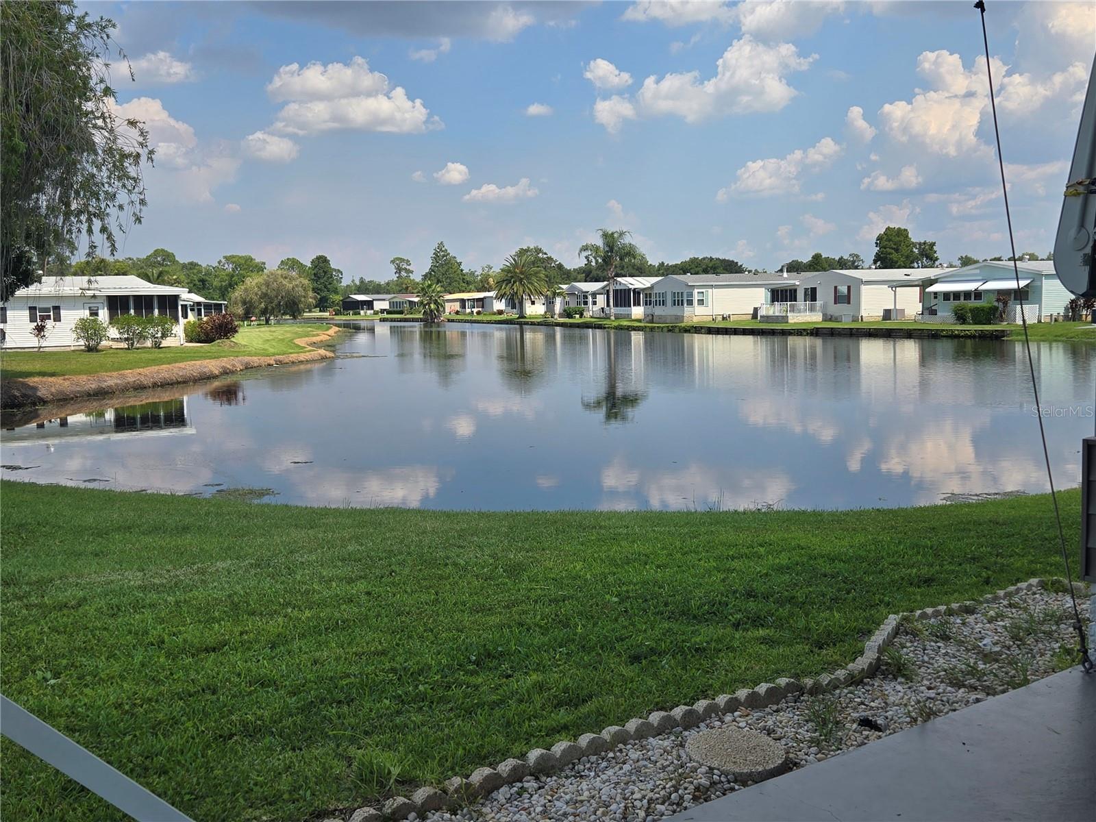 Own your own land! Resort style living for an affordable price! Run your own life as this is a community owned by the residents and we make the decisions (I live here!) The HOA includes everything except your electric bill and lawn mowing! ON THE POND! An AC'd Florida Room all across the back to enjoy the view, plus an outdoor patio! This LARGE 2/2 house has beautiful floors and textured walls, with so much space in an open floor plan with both formal dining room and a family room. There is a GARAGE with a pull-through driveway on this corner lot. No grey pipe. Inside laundry! Kitchen is full of newer appliances, slide out shelves, pantry cupboard, and corner cabinet with lazy-susan shelves. Available to see immediately! In this very friendly community, you can be as active or inactive as you choose! Gatherings at the private Pub or the Community Room, fishing on Lake Henry, gardening, pickle ball, tennis, golf, shuffle board, horseshoes, swimming in the heated pool, enjoy the hot tub or the workout room! Contact this agent for this community's website address and documents, including Rules/Regs, Application, Financial, and Bylaws. HOA INCLUDES a DVD and 2 BOXES FOR HD CABLE plus INTERNET! **55+ community with minimum age required is 50; rental max period 6 month out of a year.**
