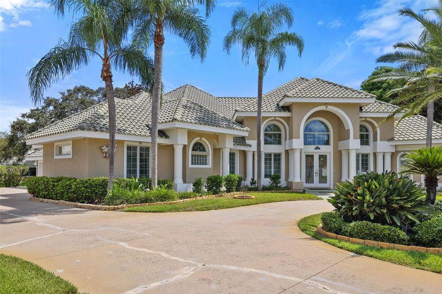 Welcome to your private oasis in a cozy subdivision near the beach! Nestled at the end of a quiet cul-de-sac, this expansive estate offers nearly half an acre of lush grounds and over 4,700 square feet of versatile living space. With 5 bedrooms plus Bonus Room (with wet bar) and 4 full bathrooms, this custom home is designed to accommodate both relaxed living and entertaining on a grand scale. Inside, you'll find a thoughtfully laid-out split floor plan featuring multiple, flexible living areas with soaring ceilings and architectural details throughout. The gourmet kitchen opens to a spacious family room and dining room while overlooking the enclosed patio with a plethora of windows to allow natural light to flow, perfect for indoor-outdoor living year-round. The primary suite offers a peaceful retreat with abundant natural light, dual vanities, and a spa-like bathroom. Additional highlights include a 3-car garage, two covered porches, and a beautifully landscaped lot with plenty of room for a future pool or garden sanctuary. Located just minutes from the beaches, top-rated schools, and all the conveniences of central Pinellas County, this home offers rare space and privacy in an unbeatable location.
