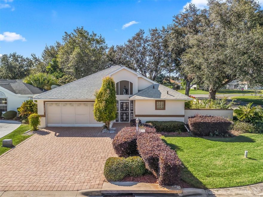 Welcome to resort-style living in the highly sought-after, gated 55+ community of Stonecrest, where elegance, comfort, and convenience come together seamlessly. This beautifully crafted concrete block and stucco residence is set on a lushly landscaped corner lot, showcasing a concrete paver driveway, charming front porch, and a wrap-around walkway leading to your own private serenity garden. A spacious two-car garage with screen cover adds practicality and ease to everyday living.  Step inside to a thoughtfully designed split floor plan offering exceptional privacy and versatility. With 3 bedrooms and 3 full baths, this home provides generous space for family, guests, or hobby rooms. Upon entering, the first bedroom—perfect as a guest suite or second primary—features its own walk-in closet and private full bath. Continue in and be welcomed by an expansive living room, brimming with natural light from numerous windows, and complemented by a convenient serving bar that opens to the kitchen. Multiple storage closets ensure everything has a place. The beautifully appointed kitchen impresses with vaulted ceilings, a skylight, granite countertops, stainless steel appliances, and a cozy eat-in area. Adjacent is a flexible open space ideal for a formal dining room or secondary living area, all leading into the tranquil primary suite. The primary bedroom offers a walk-in closet and ensuite complete with double vanities, a garden tub, and separate shower. A third bedroom is privately positioned past the kitchen, located beside the third full bathroom—perfect for guests or extended family. An interior laundry room, enhanced with a solar tube for natural light, adds convenience. Living in Stonecrest means embracing the best of the active Florida lifestyle.  Enjoy four sparkling pools, pickleball courts, softball, over 90 clubs, and endless opportunities for socializing, fitness, and fun—all just a short golf cart ride away. and no Bonds. Don’t miss this exceptional opportunity. Schedule your private showing today and step into the beautiful, vibrant lifestyle that only Stonecrest can offer!