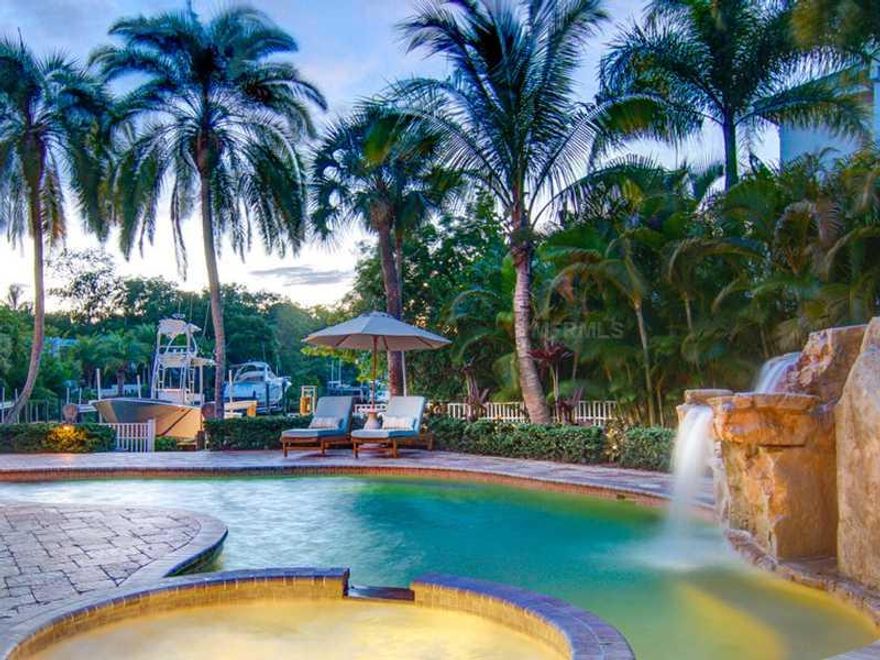 The epitome of style, this Coastal Traditional 2007 residence offers a graceful expression of luxury living, privately nestled in one of Siesta Key's most exclusive locations. Framed by majestic tall oaks, the beautiful wraparound porch welcomes you. Seamlessly combining a feeling of coastal chic with vintage beach luxury, finishes of exceptional quality and craftsmanship embellish the over 6,000 sq. ft. of living area. Extensive use of tongue--n-groove wood and magnificent coffered ceilings accentuate the design. Features include a French country Wood-Mode kitchen with granite counters, Wolf and Subzero appliances and tranquil aquarium glass windows overlooking long views of the lagoon; large living/dining room; family room; executive office; 2 wet bars;6 bedrooms; 2 laundries; large playroom and much more. Luxuriate in the grand master suite, featuring hand-scraped walnut flooring, a graceful sitting area overlooking the water, and opulent master bath. Guests can relax in their own beautifully finishedsuite.  Upstairs four bedrooms, 2 of which are suites, afford the ultimate comfort for family members. A perfect setting for entertaining, the gorgeous upstairs media room evokes the sense of a classic leisure retreat from a bygone era, with rich maple cabinetry, wet bar, and breathtaking views of the surrounding lagoon and beyond from the Brazilian Ipe wood deck. The lushly landscaped private pool and spa feature a rock waterfall and paver patio, ideal for sun-filled afternoons enveloped in serenity.