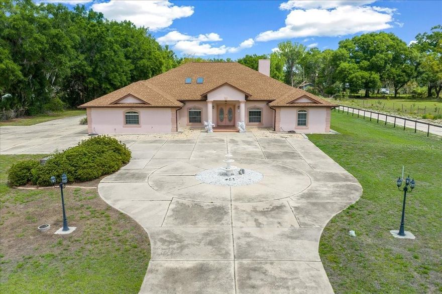 Rare opportunity in SE Ocala! Situated on 1.7 acres of agriculturally zoned land just outside the city limits, this spacious 4-bedroom, 4-bath estate offers privacy, flexibility, and room to grow—without the restrictions of an HOA.

As you enter through the private gate, you’re welcomed by a stately home featuring a circular driveway, ample additional parking, and a detached garage—perfect for extra storage, hobbies, or workspace needs.

Step inside the double front doors, where your eye is immediately drawn straight ahead to the grand great room. Anchored by a cozy wood-burning fireplace, this impressive space sets the tone for the home’s open and inviting layout. A formal dining room and a dedicated office or den flank the entry, offering both functionality and elegance. The kitchen is partially open to the great room and includes a cozy breakfast area, ideal for everyday living. Large laundry room off the garage provides more storage space and opportunity for mud room.

Designed with a desirable triple split floor plan, this home provides exceptional space and privacy, with generously sized bedrooms and abundant closet storage throughout. The expansive primary suite serves as a true retreat, featuring a massive walk-in closet, two additional closets in bathroom, and a luxurious en suite bath complete with dual vanities, a soaking tub, walk-in shower, and private water closet.

Just off the great room, a versatile bonus room with a full bath flows seamlessly into the sunroom—perfect for guests, entertaining, or multi-generational living.

Located within the highly sought-after Forest, Osceola, and Maplewood school districts, and just minutes from shopping, dining, and everyday conveniences, this property offers the perfect balance of peaceful country living and city accessibility. New roof November 2023, New HVAC September 2025.