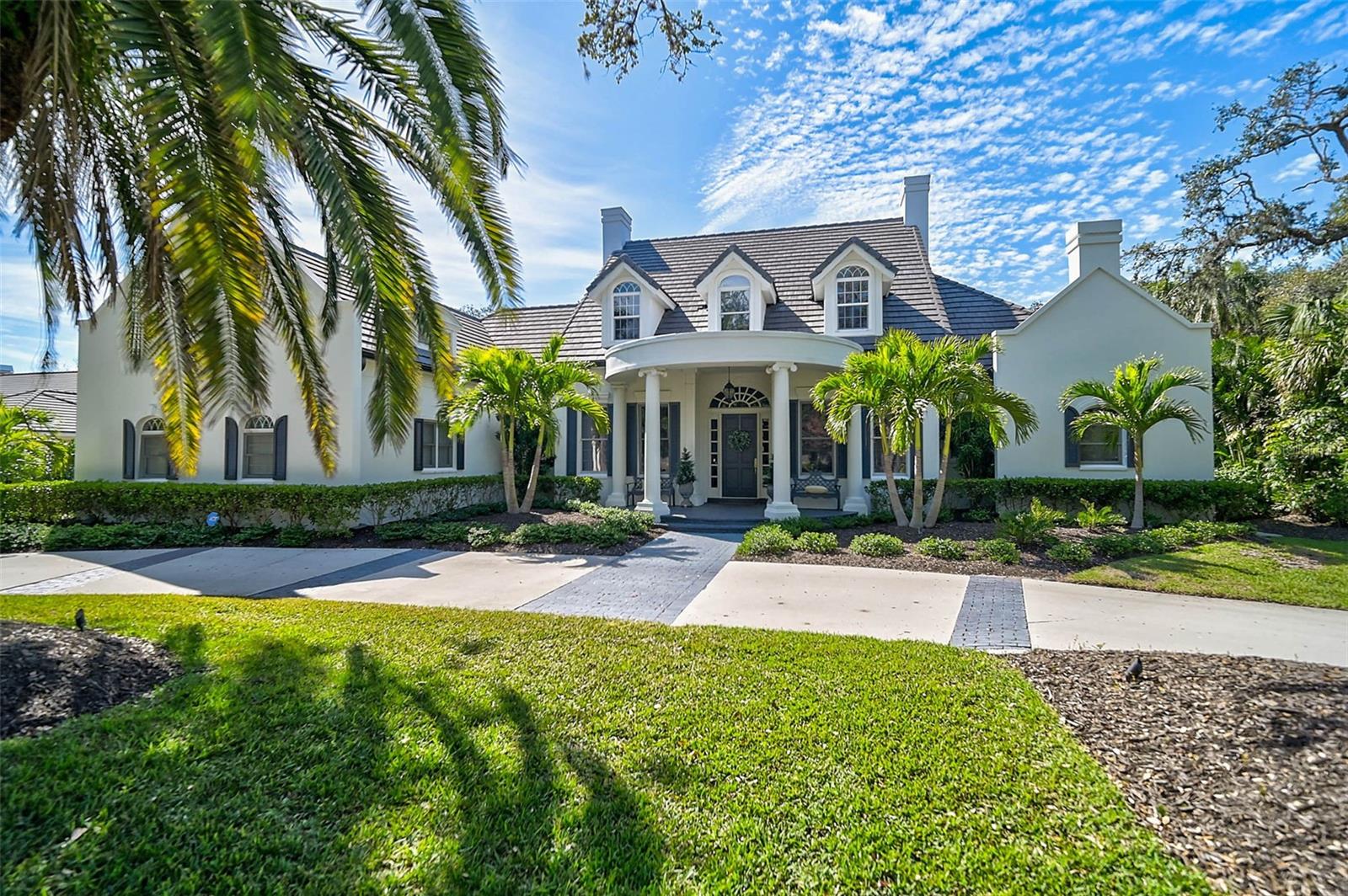**Meticulously maintained, architectural perfection, this bright, spectacular estate featuring incredibly spacious first floor living space, with 5-Beds, 6.5 Baths, private second floor family, au pair and/or guest quarters, new pool, ideal Flood Zone X location, important updates, property wide landscape renovation and a 3-Car Garage. The expansive first level has extraordinary living space: a primary suite, with TWO primary baths, and remarkable storage/closet space; an inviting living room with fireplace, a large formal dining room, a ‘light and bright’ gourmet kitchen, an eat-in kitchen area, an office, a den/media room, separate laundry room and extraordinary storage, All on the first floor. The first floor windows/doors face and/or open onto the lanai and the back gardens for massive light and enjoyment. Perfect for one level living, this special estate also offers two private, spacious second floor wings accessed by separate stairways: a second primary (in-law or au pair) on the south side and 3 bedrooms/2 baths and a delightful balcony on the north side for guests or kids! Each side with separate HVAC controls. Enjoy the expansive lanai with generous covered entertaining area, a new heated saltwater pool & spa, new retractable awnings, renovated screen cage with new panorama screens and new outdoor grill. An entertainer's dream. The back of the property backs up to the very quiet Spanish Point butterfly garden. The property’s landscape renovation provides privacy and beauty. This estate also boasts remarkable attributes including high ceilings, hardwood and marble floors, custom designed plaster crown moldings, impressive wood paneling, built-ins, wainscoting, property-wide landscape renovation (lighting, irrigation and Rainwater control system), a cozy gas fireplace and very generous storage. Updates: New roof in 2020. Others made since 2023 (last purchase): New HVAC (4 out of 5 units new since 2023); detailed List of Improvements made since 2023 and available upon request, includes but is not limited to energy savings improvements, hurricane resilience, lower insurance rates, new gutters, new awnings, new pool and equipment, Hayward pool control system and new gas pool heater; tinted windows; 500 gallon propane tank; etc. Situated just steps away from Little Sarasota Bay waters in the Tranquil West End of the highly sought after Bayside neighborhood within The Oaks Country Club community, this estate is built by Baron Construction, one of Sarasota’s Finest Custom Builders and is on a nearly half acre lot with circular driveway and wonderful curb appeal. The Oaks is a distinguished, 24hr guarded, Country Club Community which boasts many accolades including: Platinum Club of America, Emerald Club of the World, Elite Distinguished Club of the World and One of America’s Healthiest Clubs - where amenities include Three Restaurants, Ballroom, Two 18-hole championship GOLF courses, award-winning RACQUETS program with 12 Har-Tru Hydro-Grid TENNIS courts, 4 PICKLEBALL Courts, wonderful CROQUET facility, state-of-the-art FITNESS center and junior Olympic, heated community SWIMMING POOL, Bocce, Basketball Court, Playground and more! The Oaks is just minutes from nationally ranked Pine View School, the Legacy Bike Trail, area Beaches and all that Gulf Coast living has to offer. Membership is required and there is NO WAITLIST for GOLF or SOCIAL Membership. **PLEASE ENJOY VIEWING THE 3D VIRTUAL TOUR and AERIAL VIDEO**