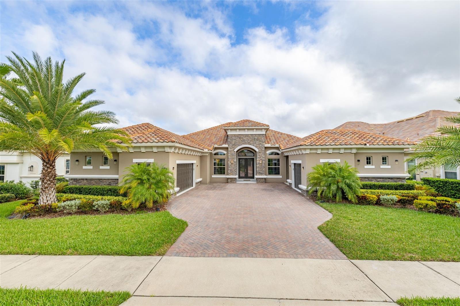 Welcome to a truly exquisite single-story residence in the coveted and exclusive gated waterfront community of the Isles of Lake Hancock. Step inside to an opulent foyer that opens into a grand, light-filled living space with 14-foot double tray ceilings, engineered hardwood and luxury tile flooring, and expansive windows fitted with remote-controlled blinds. The open layout flows seamlessly through the formal dining room, dedicated office, and spacious living area.
The chef’s kitchen is a standout centerpiece, thoughtfully designed with custom cabinetry, premium Monogram stainless steel appliances and an oversized pantry for additional storage. The private primary suite is positioned away from the secondary bedrooms and offers a peaceful retreat with an oversized spa-style bath, a luxurious walk-in shower, and a custom-designed closet. An extended den acts as the perfect reading nook or morning lounge, leading directly to your covered lanai and fenced backyard. Entertain in style with two built-in theatre/streaming projectors, a high-end electric screen enclosure, outdoor heating unit, and custom entertainment cabinetry. The property also features dual garages—a two-car and a single-car—finished with sleek smoke grey epoxy flooring, providing flexible space for parking, a home gym, or elevated storage. The garage is equally impressive, showcasing smoke grey epoxy flooring, car lift capability, and a dedicated space prepped for an in-home golf simulator—perfect for golf enthusiasts.
Beyond the home, residents enjoy direct access to two man-made lakes in a nationally recognized water-skiing community, known for hosting world-class tournaments annually. The location also offers close proximity to Walt Disney World, upscale golf courses, premier shopping and dining, and features a community playground, making it ideal for both recreation and family-friendly living.
This artistically curated home is more than just a residence, it’s a statement in luxury, design, and lifestyle. Don’t miss your opportunity to own a rare gem in the exclusive community of the Isles of Lake Hancock.
