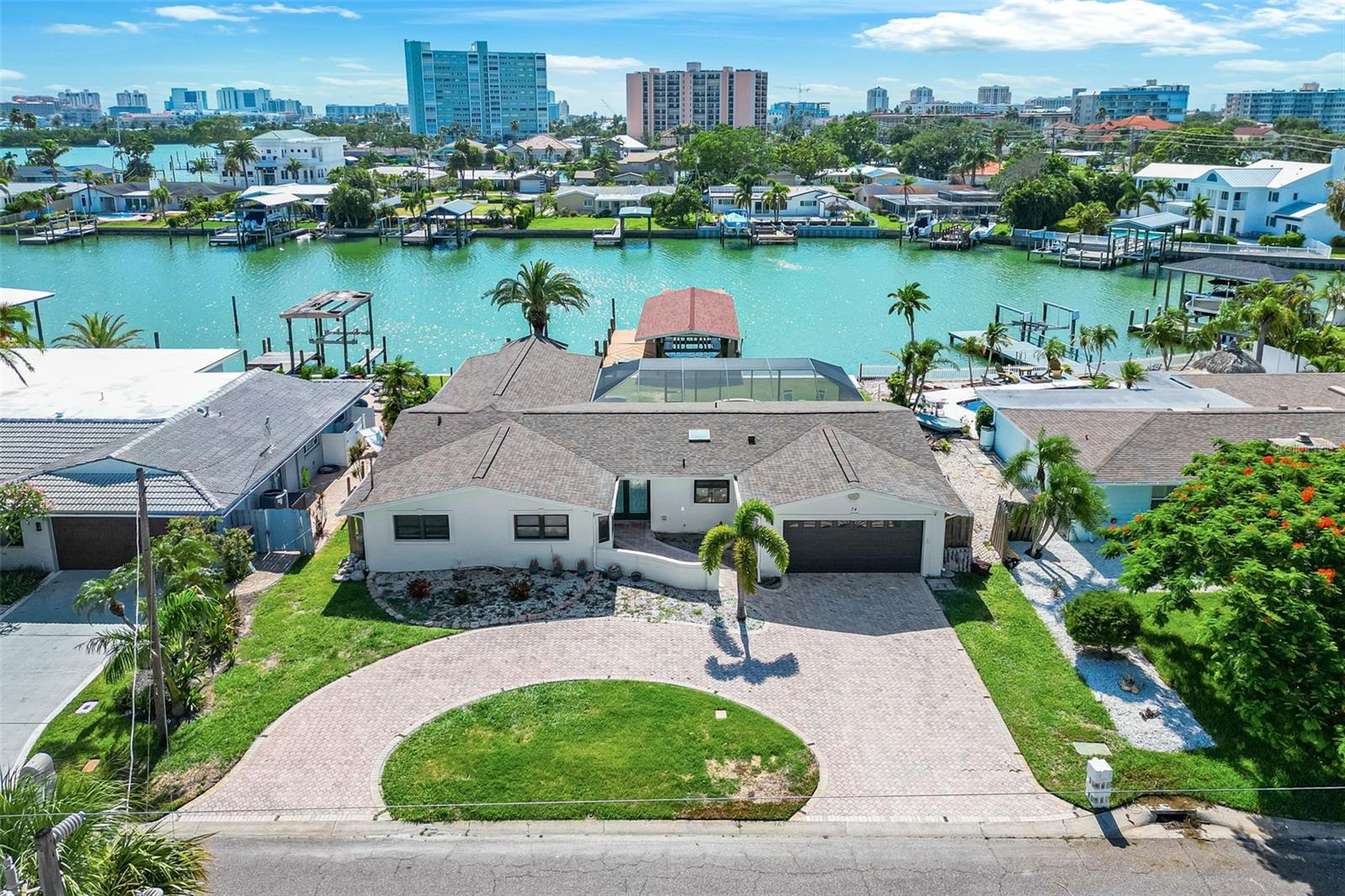 Opportunity Knocks! Island Estates Clearwater Beach Waterfront on an end finger peninsula. Large open and bright floorplan with split bedrooms and an 11' island dream kithen. Oversized master suite, has been added on and reconstructed. It has 3 walk-in closets double doors that open up to the screened pool patio and a sitting area overlooking the intercostal. Seller will finish master bath or give a buyer credit with the right offer. Screened heated pool with built in Jacuzzi/spa and outdoor shower area. Oversized, covered dock/boathouse made with Evergrain composite forever board accommodates 3 large boats, an in water slip up to 55’ feet, a covered 32’ foot with 14k lb lift with remote and an additional 55’ slip for 3rd boat, guest boat or jet skis. boat or kayak accross to amphitheater to watch live concerts or enjoy from large patio/lanai. New seawall with higher elevation completed in 2023. Amazing sunsets and Stunning views. Home also featured an oversized 4 car garage with ample storage space.