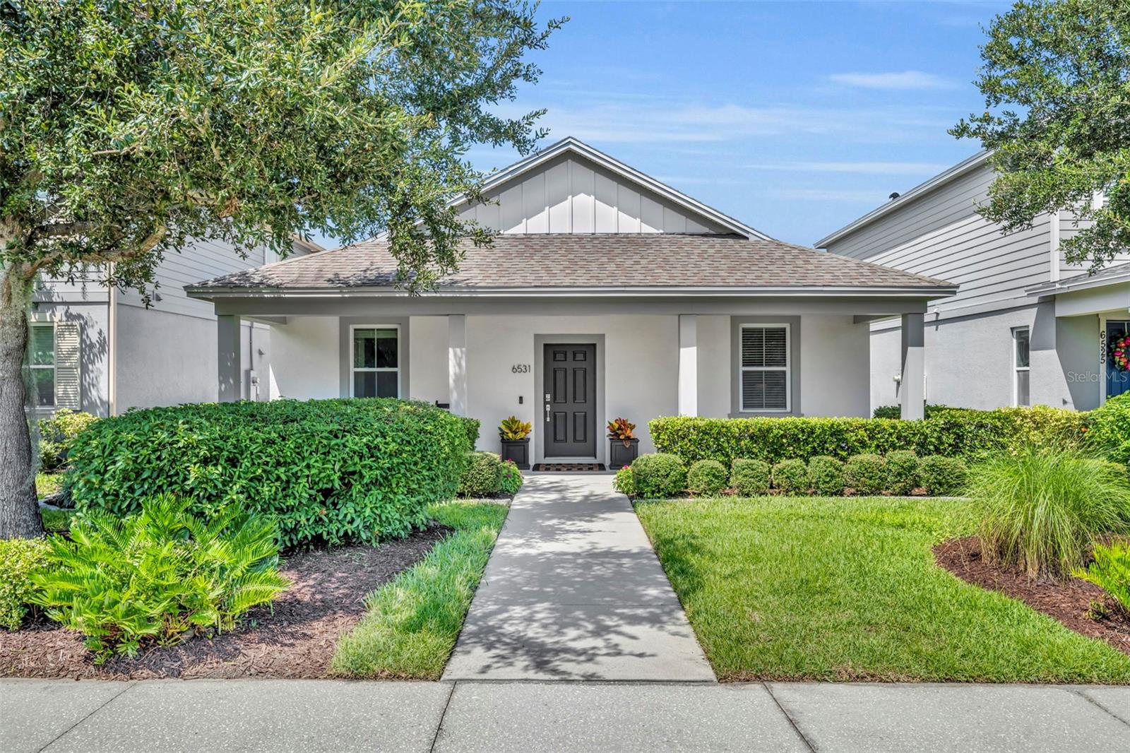 This charming home, located in Winter Garden’s desirable Hamlin Reserve community, overlooks a peaceful park, which can be fully appreciated from the welcoming, covered front porch. As you step inside, your guests will be greeted by the soft entry of a foyer, immediately adjacent to a formal dining or living space with recently updated lighting. Beyond that, the kitchen seamlessly opens to the general living space with views of the backyard oasis. The kitchen, like the rest of the home, features a neutral color palette, including white kitchen cabinets, gray, white, cream, and black speckled granite countertops, brushed nickel hardware, new neutral interior paint, and stainless steel Whirlpool kitchen appliances. Highlights of this space are a five-burner gas range, a walk-in pantry, and a sizable kitchen island with new overhead pendant lighting and seating for four. The general living space provides plenty of room within which you may relax or entertain. Sliding glass doors open to a large covered back patio with newly installed brick pavers, a summer kitchen, outdoor TV with a pivotal mount and a built-in, gas-fueled fire pit for enhanced outdoor enjoyment. Let your kids and dogs play in the backyard without fear, as the owners installed a new privacy fence around the perimeter of the lot. Back inside the home, the desirable floor plan features a private primary suite split from the alternate bedrooms and bathroom. The alternate two bedrooms share a sizable full bathroom with hallway access at the front of the house with one of the bedrooms looking out over the green park space. The private primary suite is located at the rear of the home and includes a long vanity with double undermount sinks, extensive cabinets and drawers for organization, a solid surface countertop, an expansive almost countertop-to-ceiling mirror, a walk-in shower with a glass enclosure, and a large walk-in closet. The laundry room has a sizable capacity for storage and is conveniently located in the heart of the home. The rear-entry oversized two-car garage includes a new epoxy finished floor, dedicated EV charging station and is accessible from the back alley, adding even more charm to the front elevation. Abundant street parking is available for guests. Additional upgrades by the current owners include fresh paint, several new light fixtures and fans, a new Rinnai tankless water heater, new sod and more! The Hamlin Reserve community offers a clubhouse, pool, playground, and parks with picnic tables for residents’ use and enjoyment. Living at 6531 Orange Cream Alley in Hamlin Reserve means embracing a lifestyle centered around convenience, community, and connectivity. You’ll have local shops, dining, entertainment, and plenty of outdoor and recreational spaces just steps from your front door. Plus, the location offers easy access to major attractions and healthcare—all making it a highly livable area. Call to schedule your private showing now.