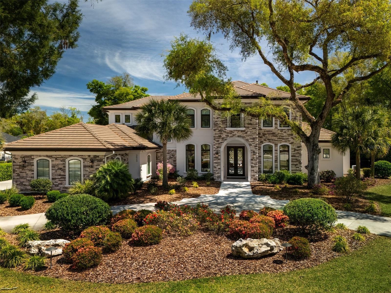 This stunning custom home located in Oakmont is situated on a sprawling acre lot, with 7131 sq. ft. of luxurious living space and nearly 10,000 sq. ft. under roof. Built by Tommy Waters in 2019 this home has been meticulously updated in recent years adding designer charm to an already magnificent home. Featuring 5 bedrooms, 5 baths, 3 half baths, an office, game room and a golf simulation/media room, this home ensures ample space for all of your family and friends. Welcomed by custom iron doors, enter this exquisite home with soaring two story ceilings in the entry area and an open concept layout that seamlessly blends elegance and functionality. The gourmet kitchen boasts high end Wolf appliances, sub zero fridge, custom cabinetry, double islands, dual sinks and ice maker, all making it a chef's dream. Located right off the kitchen, a hidden pantry with custom shelving and full size freezer has ample storage for the whole family. Also conveniently off the kitchen is a full wet bar/butler's pantry featuring a custom barrel ceiling, full-size wine fridge, ice maker and custom cabinetry. The adjacent eat in breakfast nook and grand living room create the perfect setting for entertaining or relaxing with family. Head through double doors to the game room featuring multiple tv's, pool table, shuffleboard and a wet bar with beverage fridge making it the perfect hang out spot. Across the game room is a large guest bedroom with en-suite bath and walk in closet. On the other side of the first floor living space you'll find a large study with built-ins and the impressive owner's suite. The updated custom closet features floor to ceiling mirrors, ample cabinetry and a large center island. The owner's bath features his and hers WC's and double vanities, marble tops, free standing tub and a marbled tiled walk in shower. Heading upstairs you'll find the state of the art golf simulation room that provides endless entertainment for casual or competitive play that is truly a golf lover's dream. While the simulator includes a variety of virtual sports, the space can also easily be reimagined as a media room for movie lovers. The upstairs landing area features a half bath and a newly installed study area with custom desks and endless cabinetry. Three large bedrooms each with their own en suite baths complete the upstairs space. The outdoor living area features an expansive screened in travertine deck with a summer kitchen that includes a grill, deep fryer, ice machine and beverage fridge. A gas burning fireplace, seating area and tv complete this side of the outdoor space. Enjoy the salt water pool and oversized spa featuring waterfalls and spillovers. Reimagined by the current owners, the backyard features a fire pit area overlooking a neighborhood common area, a half basketball court and custom landscaping and lighting. A 3 car garage with Tesla charger has room for all your cars and toys. A natural gas generator has also been added for peace of mind. Oakmont amenities include a resort style clubhouse, pool, fitness center and tennis and basketball courts. This home is truly one of a kind!