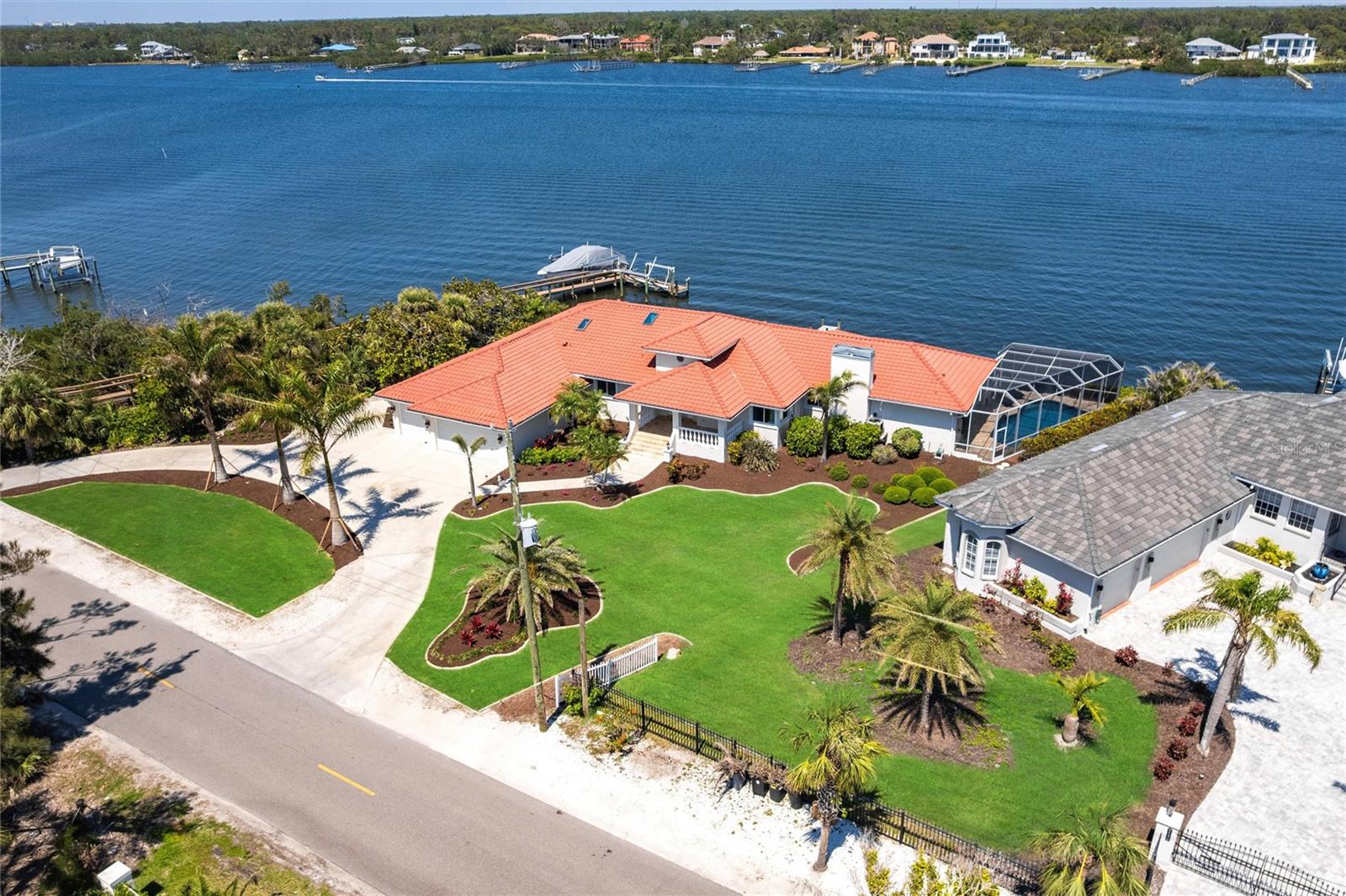 Welcome to 8115 Manasota Key Road—an extraordinary waterfront estate where refined luxury and coastal living converge. Perfectly situated on Lemon Bay with the beach directly across the street, this one-of-a-kind property offers an unmatched lifestyle—sunrise mornings on the bay, sunset walks on the beach, and effortless access to boating, dining, and everything this exclusive island has to offer. From the moment you enter, you're greeted by a grand foyer that sets the tone for the rest of the home. Soaring ceilings and a stunning wood-burning fireplace anchor the expansive living space, creating a warm yet elegant atmosphere. The open-concept layout flows seamlessly into the heart of the home—a spacious, thoughtfully designed kitchen with ample counter space, beautiful cabinetry, and a layout that invites both daily living and upscale entertaining. Nearly every room captures a breathtaking view of the water, bathing the interiors in natural light and offering a constant reminder of the peaceful waterfront setting. With 5 bedrooms—including two luxurious en-suites—2 guest bedrooms, a spacious office plus a formal dining room and a charming breakfast nook, there’s plenty of space to host friends and family. The indoor-outdoor connection is truly exceptional. Step outside to a newly resurfaced, pool surrounded by a private screened-in lanai, where you can relax, entertain, and take in the panoramic water views of Lemon Bay. Whether you're watching dolphins play, casting a line from your dock, or just enjoying the poolside, every moment feels like vacation. The home also features a 156-foot concrete seawall with private dock, providing direct boating access to the Intracoastal and quick trips to Stump Pass and the Gulf of America. Additional upgrades include new wide-plank floors, hurricane-rated windows and doors, fresh interior and exterior paint, a 2022 concrete tile roof, and professional landscaping by Hazeltine. The oversized three-car garage and spacious circular driveway complete this exceptional house. Whether you’re looking for a luxurious retreat or a show-stopping entertaining home, 8115 Manasota Key Road delivers on every level. Schedule your private showing today and experience the coastal lifestyle at its finest.