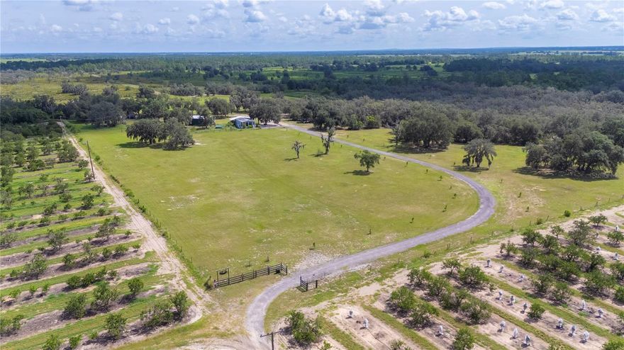 Discover the potential of this 20+ acre property in Fort Meade, ideal for homesteading, ranching, small-scale commercial use, or as a private family compound. The land includes fenced pastures, barns, sheds, a 1+ acre pond, and a well-maintained residence - set back for privacy among orange groves. The perimeter is fully fenced, and the drive is lined with young Longleaf Pines beside Bahia grass pastures. A full-length screened front porch offers panoramic views across the property.
Inside, the open-concept layout connects the kitchen, living, & dining areas. The kitchen features a central island & a gas range fueled by a 50-gallon propane tank. Continuing, find a full bath to the left, laundry/pantry closet to the right along with the master suite with walk-in shower. A second bedroom/office opens to an expansive 16x33 rear screened porch, extending the living space & perfect for entertaining, complete with ceiling fans, mounted TVs, & pond views.
Off the porch is a fenced, irrigated food forest & herb garden. A separate building includes a full bathroom & RV hookup with septic, water, & 50-amp service. North of the home is a 24x40 insulated metal pole barn with multiple work zones. One bay has a roll-up door for storage; another features a canning/processing kitchen with a 100-gallon propane-fed commercial oven, mini-split, tankless water heater, three-compartment sink, dishwasher, washer/dryer & a walk-in pantry with its own AC—designed for conversion to cold storage. Extra outlets & upgraded electrical in place to accommodate the various activities.
To the west are 3 large animal pens with water, a 20x25 metal barn with stalls & electric, and 3 hog pens with water. Additional structures include a supply shed, workshop barn with electrical access, & a She Shed with water, AC, & electric. The poultry zone includes 9 fenced pens with coops and nesting boxes. A 22x60 fenced garden with amended soil & irrigation is ready for planting. Nearby are 3 more metal storage buildings. A 25x36 divided kennel/pen & 30-amp RV hookup, both with water, to the east.
A 1/3-mile walking/ATV trail runs through the Oak Hammock north of the pond, ideal for wildlife watching or livestock watering. The homestead is secured with flood lighting & backed by a 24KW Generac generator connected to a 500-gallon underground propane tank. The infrastructure is in place - just bring your vision.
