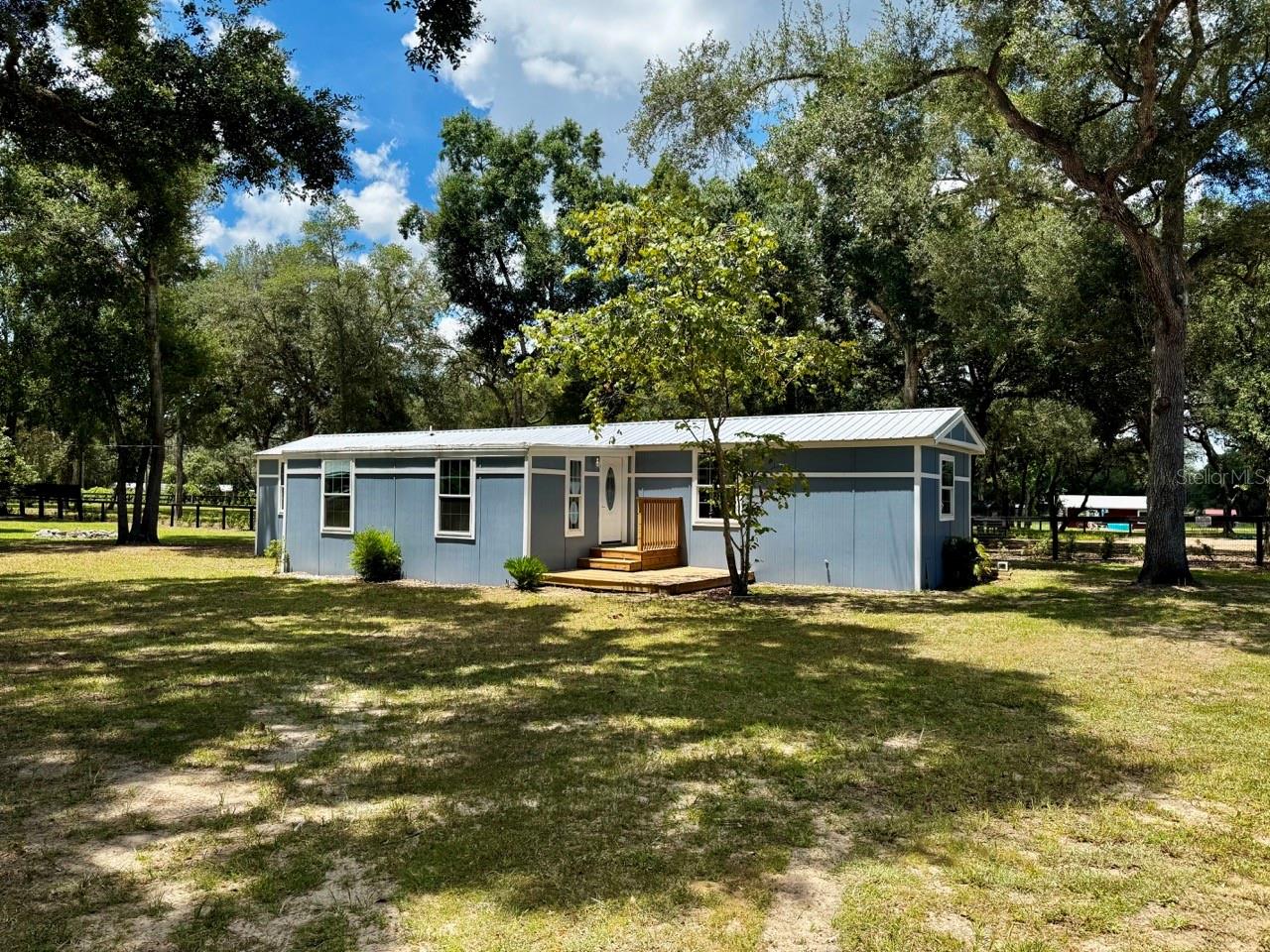 Find yourself at home, steps away from the Forest’s edge, in this beautifully renovated mobile home with a living room addition. This 3/2 home has been updated, inside and out. Improvements include a new metal roof, Hardiboard vertical siding, new drywall, insulation, and subfloor. Has new LVP flooring throughout, new doors, new double-paned windows, brand-new stainless appliances, butcher block countertops, LED recessed lighting, tiled showers, a tankless water heater, and a brand-new HVAC system. Has 2 detached storage buildings with new metal roofs, W/S/P connections, on its separate 50-amp breaker, if you should choose to reconnect. Enjoy the FL summer evenings on your deck, drinking your favorite beverage, with the occasional tune of the neighboring donkey family. Property has 200amp service with new breakers, and most wiring to home has been replaced. A loquat, citrus, and cattley guava tree are found on the property, and all mature trees have been trimmed back. Located in Salt Springs, just minutes away from multiple boat ramps to lakes, rivers, and springs, and miles of hiking/atv trails to explore through the Ocala National Forest. MOVE IN READY!