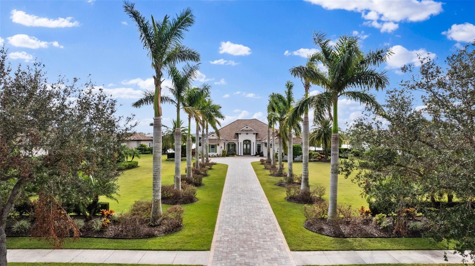 Welcome to The Concession, a unique, serene and peaceful community that features its prestigious and best private golf course on Florida’s West Coast and host to the World Golf Championship PGA tournament in 2021. Come discover this luxurious West Indies style custom home by Lee Wetherington, The Windsong Model (prize winning floor plan) very congenial with great curb appeal, away from the street and recessed deep into the one acre lot with plenty of space between wonderful neighbors at the end of an inviting driveway flanked by twelve tall Royal Palms.
As you step in, a stunning panoramic view of the lake over the living room immediately catches your eye, then the open room concept is revealed… Seamless living into kitchen, dining room and living room combined, perfect for entertaining, not to mention easy indoor-outdoor flow through large telescopic sliding glass doors. Elegant tray ceilings and beautiful classic yet modern twelve columns adorn the open space, hallway and into entrance of master quarters. The kitchen flaunts beautiful Cambria Quartz counter and a waterfall finish; Wolf gas stove, microwave and wall oven, Miele quiet dishwasher and Sub Zero Refrigerator/freezer, perfect triangle work space with perfect placement of pantry. For a more casual setting, move into the bonus room with your favorite snacks from the adjacent kitchen for game or movies nights with surround sound and accented ceiling. This room conveniently opens up to the lanai and outdoor kitchen with two sets of sliding doors.
You will enjoy the spacious lanai with a southern exposure, travertine pool deck grouted and sealed, an infinity spa, a geometrically appealing saltwater heated pool with nearby sun bathing space. You'll enjoy the magnificent sunrise skies with coffee. For nature loving people, you will love the view of nesting Sandhill cranes and other aquatic fowls along the natural shoreline right outside the lanai, keep your binoculars at hand and a camera! For the winter months on the lanai, enjoy by cozying up to the circular travertine gas fireplace.
Behind the outdoor kitchen and inside the lanai is an attached private casita with a large panoramic view window on the lake showcasing an attractive tray ceiling with fan, large sitting area and decorative brick wall, perfect for your V.I.P guests. The west wing of the house has two spacious bedrooms and a very functional laundry room with Cambria Quartz counter tops, and a 3 car garage at the end of the hall.
The east wing of the house has an office with a storage closet on each side, and again a great view from the exterior French doors that open onto the lanai for a nice break from work, or just to step out for a phone call. Then, you have the well designed master bedroom with tray ceiling and chandelier, French doors opening onto the lanai, her Hollywood closet is a WOW - it’s every woman’s dream, just come see it! His closet has beautiful dark wood cabinetry with drawers, counter space, shoe shelves, clothes hamper, plenty of storage and a window high above the cabinets. The master bath is just the right size, large doorless shower with glass from floor to ceiling, and there is a simple but refreshing outdoor shower. Also featured is an extra long soaking bathtub, double vanities with lighted floating mirrors separated by his and hers tower cabinet.