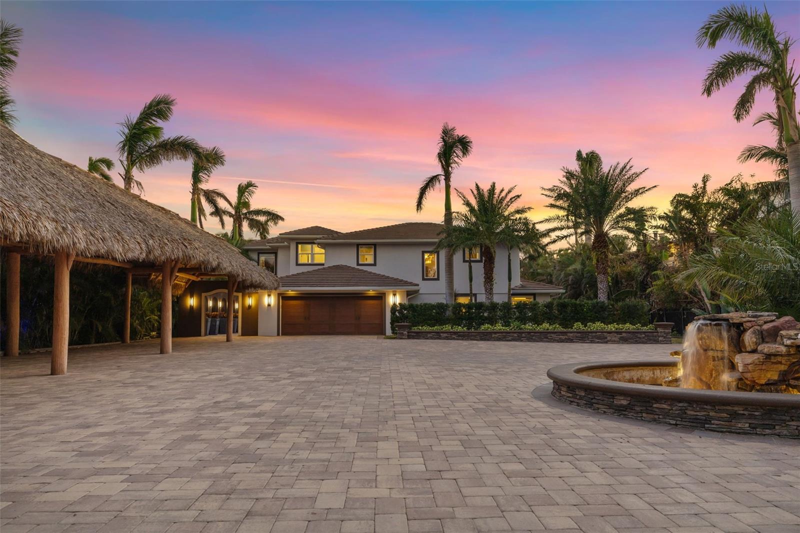 Exquisite waterfront estate with unmatched luxury and privacy. Welcome to this stunning waterfront property set within a private, gated entry, framed with lush, mature plantings that lead you down a stone-paved driveway with a beautiful circular stone fountain. This exceptional residence offers a seven-car tiki carport plus a two-car enclosed garage, ensuring ample space for all your vehicles and guests. On a breathtaking waterfront property, this home features a newer seawall cap, ensuring durability and enhanced coastal protection. The whole-house generator ensures your peace of mind, providing power during any unforeseen interruptions. Impact glass windows and sliders offer added security and storm protection while flooding the home with natural light. Entertaining is a breeze with the expansive living areas, offering large spaces that flow effortlessly for gatherings. An elevator is conveniently on the first floor for ease of access to the second-floor rooms. The luxurious primary suite is a sanctuary with beautiful travertine floors, 10-foot ceilings, custom built-in bed, expansive windows and doors with electronic window blinds and a mini kitchen completed with refrigerator, cooktop, wine refrigerator, sink and dishwasher. The en-suite, spa-like, bath features a large soaking tub, an oversized glass steam shower, two vanities and two large walk-in custom closets to satisfy all your storage needs. From the bedroom, you can go out onto the private balcony, where you can soak in the stunning views of the Gulf. There are four additional private bedrooms and four baths, making it the ideal home for larger families, those who like to entertain guests or those just seeking extra space. The heart of the home is the newly updated chef’s kitchen, equipped with top-of-the-line appliances, including a 48-inch Wolfe gas stove and 48-inch Sub-Zero refrigerator. Custom built-in features, elegant finishes and tranquil water views make this space special. A second fully equipped kitchen can be used when hosting special events and is ideal for creating culinary masterpieces. Step outside into an entertainer's dream. The expanded 8-foot deep pool with spa and sun deck offers the ideal setting for relaxation or entertaining guests. A multi-level travertine patio provides ample space for outdoor dining and lounging, while an outdoor kitchen and bar create an ideal space for alfresco meals. For the ultimate waterfront experience, unwind in the 12-by-12-foot tiki hut with seating, offering panoramic views of the serene water. As the sun sets, gather around the stone gas firepit to enjoy the peaceful ambiance and beautiful surroundings. This estate is a blend of privacy, luxury and convenience, offering an unparalleled lifestyle in an extraordinary location.