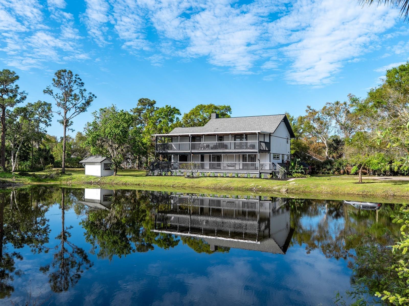 One or more photo(s) has been virtually staged. A private lakefront retreat nestled on 1.8 acres right in the heart of Sarasota! This serene sanctuary provides the perfect blend of seclusion and accessibility, inviting you to escape the hustle and bustle while being close to all the amenities you need. Located west of I-75, near Cattleman Road, this property has 4-5 bedrooms, a den/study, 3 bathrooms, and a detached, climate-controlled 1500 square foot garage that accommodates 4-5 cars, offering endless possibilities. The hobbyist will find it a versatile workshop, while the visionary can adapt it to meet their needs, enhancing its potential and value. The main house has a wraparound porch surrounding the first floor, featuring three French doors blending the indoor and outdoor spaces. A great room combines living and dining areas and boasts clerestory and twin picture windows, two-story ceilings, and a wood-burning fireplace. The kitchen is fully equipped with nearly new stainless-steel appliances from GE. It has ample cabinetry designed in a farmhouse style, complete with stained glass accents. Additionally, there is a built-in pantry and under-stairs storage for even more convenience. A center island on tiled flooring includes a breakfast bar and extra cabinets for added organization. A separate den/study has double pocket door privacy, window bench seating, and direct access to one of two primary bedrooms. This first-floor suite overlooks the lake and has a built-in closet. This wing also includes a flex room that could be converted into a beautiful walk-in dressing closet (refer to the virtually staged photo). The updated bath has room for an enlarged vanity to accommodate double sinks. This area could be transformed into the ideal first-floor Owner’s suite by integrating these rooms with continuity. A landing on the second floor leads to the bonus room, which overlooks the main living area. The primary suite on this floor has been upgraded and features a balcony and a walk-in closet. A stylish barn door separates the en suite bathroom, which includes a free-standing vanity, dual sinks, and a spacious walk-in shower with a glass door. Upstairs is an updated bathroom and two additional bedrooms, each featuring a walk-in closet, a laundry room, and French doors to a balcony. Step onto one of the two decks to experience stunning sunrises over the lake. The lower deck has just been reinforced and refurbished. The house is said to contain a 3-foot concrete block wall and concrete pads supporting steel floors and beams, originally built to accommodate these beams for added structural support. Surrounded by stately oaks on an expansive piece of land, this remarkable home offers plenty of room for outdoor activities and the possibility of adding a pool without any deed restrictions. So, bring your boat and RV! The location is near Detweiler’s Farm Market, UTC shopping, and various dining destinations. It is also close to several county parks, including the Celery Fields, which borders Ackerman Park. This 360+ acre area is well known to locals for its diverse wildlife and wetlands, providing opportunities for nature watching and exploration. Visitors can enjoy activities such as walking along two boardwalks, fishing, and kayaking.
