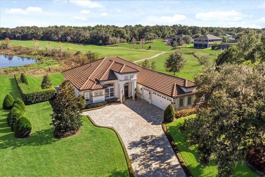 Lake and golf views! Breathtaking panoramic views from nearly every room define this beautiful 2018 custom-built 3 bedroom, 3 bath home plus bonus room and office, set on a highly sought-after premium cul-de-sac lot of over half an acre. The gorgeous property overlooks Lake Nicholas and the 16th hole of the RedTail Golf Course within the gated luxury community of RedTail at Heathrow Country Estates. From the moment you enter, walls of windows draw your eyes to the shimmering lake and rolling greens beyond. This well-maintained residence offers nearly 2,700 sq ft of refined living with an open floor plan, extensive upgrades, timeless design, hardwood floors, smart technology, and energy-conscious features. The stunning great room showcases high wood-beamed ceilings and a striking floor-to-ceiling stone gas fireplace with built-ins, creating the ultimate ambience. The chef’s kitchen and dining areas are perfect for entertaining, boasting a 16ft island with exotic granite, stainless steel appliances, designer range hood, 6-burner gas cooktop, and a desirable walk-in pantry. The primary suite offers a peaceful retreat with sweeping lake and nature vistas, dual walk-in closets, and a spa-inspired bath with luxurious Italian Carrara marble double vanities. Two additional bedrooms and baths with Carrara marble are located in the opposite wing. A dedicated library/office, flexible bonus room, and laundry room are well-appointed with bespoke cabinetry. Enjoy seamless indoor-outdoor living through expansive sliders opening to the extended paver patio with motorized screen enclosure, ideal for enjoying Florida’s year-round climate. Additional highlights include an approx. 920 sq ft 3-car garage with epoxy floor, larger doors, attic pull-down stairs, workshop/storage space, plus an impressive exterior with expansive paver driveway, tile roof, Low-E double-pane windows, smart irrigation, and security lighting with cameras, surrounded by serene natural beauty. Residents enjoy clubhouse dining and socials, fitness center, tennis courts, resort-style pool, scenic walks and optional championship golf course. Don’t miss this extraordinary opportunity to own one of the community’s most coveted lake and golf-view estates. Schedule your private showing today!