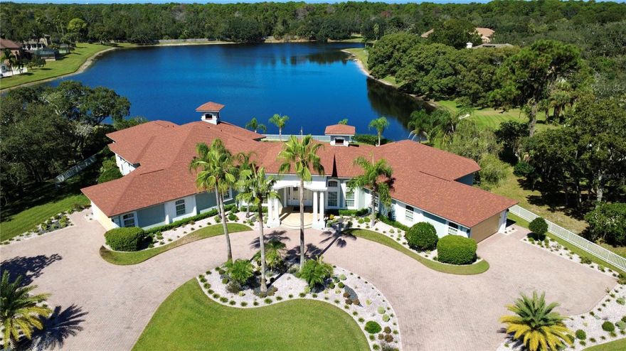Welcome to this stunning lakefront estate on nearly an acre of professionally landscaped grounds. The estate sits on a spring-fed lake that backs up to a state nature preserve and is just three miles from the ocean. This custom-built masterpiece invokes the sophistication of an updated smart-home. It comes FULLY FURNISHED and has a BRAND-NEW ROOF (2025). You are welcomed through the double glass front doors by a stunning infinity lake view and fourteen-foot coffered ceilings which continue throughout the palatial interior. Marble flooring, marble walls, and quartz counters are just a few of the meticulous details. This home is the epidemy of a smart-home with a top-of-the-line Control4 home automation system. With a touch of your finger from your cell phone you can control the lights, motorized shades, whole house surround sound, TV’s, front door intercom/camera, AC thermostats, smart door locks, and exterior security cameras from anywhere in the world with an internet connection. This immaculate SINGLE-STORY retreat includes 5 bedrooms, each with their very own en-suite bathroom and walk-in closet. There is a great room, family room, sitting room/library, formal dining room, a home office with custom cabinets, a meditation room, and your very own exercise room. The master bedroom is for the most discerning of owners. It has a stunning view of the spring-fed lake, double trey ceilings, a mini bar with refrigerator, hardwood floors, a chandelier, as well as his and hers walk-in closets. The master bath has marble floors, soft close drawers, a freestanding soaker tub and a walk-in frameless glass shower with rain head plus multiple heads. Other distinctive features in the home include; Motorized shades. Cove lighting with various colors to suit your mood. Faux painted walls. Imported chandeliers. Four ecobee smart thermostats making it four-zone energy efficient. In the kitchen there is a sensor touch main sink, a second prep sink, a Sub-Zero refrigerator and an Insta-hot faucet. There are two gas fireplaces, both remote controlled. There is also a Tesla charging station in the garage. There are actually TWO two-car garages big enough for four cars, plus extra space for a golf cart or other toys. Outside offers privacy and luxury with a RECENTLY REMOLDED AND RESURFACED POOL (2024) that overlooks amazing sunsets on the lake. There is lanai with outside sink, outside surround sound, extensive landscape lighting, mature fruit trees, and over 1500 square feet of raised patio space. Located in the exclusive 24/7 guard staffed gated community of Lake in the Woods, which has tennis courts, pickle ball court, playground, and two lakes where canoes are allowed. Wild life abounds in this serene community; Turkey flocks, deer, ducks, egrets, sand hill cranes, ospreys, golden eagles, humming birds, and hawks. The community is conveniently located just 7 minutes to Weeki Wachee Springs State Park for kayaking and paddle boarding. 10 minutes to Hernando Beach for boating and deep sea fishing. 15 minutes to Pine Island Beach for swimming and sunsets. 45 minutes to the Tampa International Airport, and less than 60 minutes to St. Pete Beach, which was named the number one beach in America.