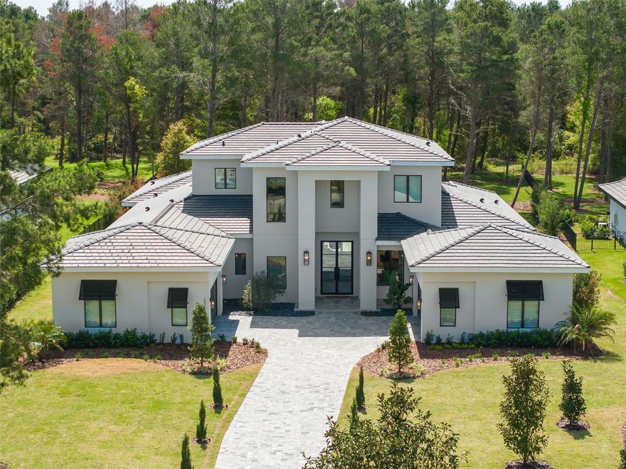 Experience the epitome of luxury living at its finest in the exclusive guard-gated country club community appropriately named Bella Collina, one of Central Florida's most sought-after residential neighborhoods. Nestled on a 1-acre estate preserve lot, this contemporary-crafted Lemans floor plan by Davila Homes boasts an impressive 5,114 square feet of living area and a total of 7,710 square feet under roof.
As you step through the double doors, the open foyer welcomes you, with a well-appointed office on the right. The gourmet kitchen is a chef's dream, featuring top-of-the-line Fisher & Paykel appliances, an 8-burner gas stove, an oversized island, and a custom-built wine wall. Adjacent to the kitchen, you'll find a half bath and a game room with pocket corner sliding doors that offer stunning views of the covered porch and lanai, complete with a custom-built summer kitchen and remote-control screens. A guest suite with a full bathroom provides comfort and privacy for your visitors.
The oversized laundry room features an elevated washer & dryer and an oversized back pantry, making household chores a breeze. The great room exudes tranquility with its natural earth tones and a soothing gas fireplace, while a wall of glass sliders leads to the covered lanai and a resort-like solar pool and spa.
The generous primary suite offers ample space for a sitting area and a spa-like primary bathroom with dual sinks, a soaking tub, and an oversized walk-in shower that leads to a customized walk-in closet. A glass stairway takes you to the second floor, where you'll find a spacious media loft, three generous en-suite bedrooms, and a covered balcony with retractable screens.
This sophisticated home is equipped with state-of-the-art features, including a Crestron electronics system, electronic drapes and shades, a built-in ground-level trampoline, pre-plumbing for a fire pit, and oversized fenced backyard with extensive landscape lighting. As the owners never moved in, you can enjoy all the upgrades without the wait of building from scratch! Enjoy all of the amenities Bella Collina has to offer including two restaurants with outdoor patios, 5-star spa, championship golf course, 5 tennis courts, basketball court, 3 pickle ball courts, fitness center with complimentary fitness classes for residents, a pool complex with bar and cabanas and year-round culinary and social events.