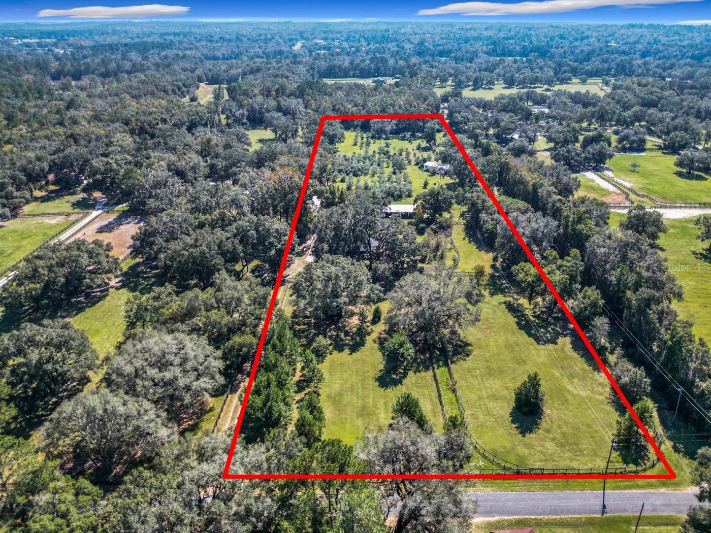 One or more photo(s) has been virtually staged. 10-Acre Farm with Two Homes in Ocala’s most desirable NW Horse Country. Located just minutes from HITS and the World Equestrian Center, this beautiful 10-acre farm offers a potentially perfect setup for equestrians, farmers or multi-generational living. Tucked beneath the shade of majestic oak trees, the main residence is a fully renovated 3-bed, 2-bath home featuring a new roof, new HVAC, new appliances, new hot water heater, remodeled bathrooms, granite countertops, fresh paint, and luxury vinyl plank flooring throughout. Stylish and move-in ready! The second home, a 2001, 3-bed, 2-bath double-wide mobile, also boasts recent updates including a metal roof, new HVAC, LVP flooring, appliances, ceiling fans, fresh paint and new skirting. At the heart of the farm is horse barn with 3 possible stalls, an office/tack room, grooming and wash area—ideal for daily care and training. Two fenced pastures with plenty of room to add an arena or more pastures. Additional infrastructure includes a spacious 20’ x 60’ workshop perfect for equipment, and a 12’ x 16’ storage building for added convenience. Adding to the property’s appeal is a grove of mature olive trees, offering a unique opportunity for passive income or simply a serene natural backdrop. While the homes are updated the rest of the farm needs some TLC to be brought back to it's full potential.