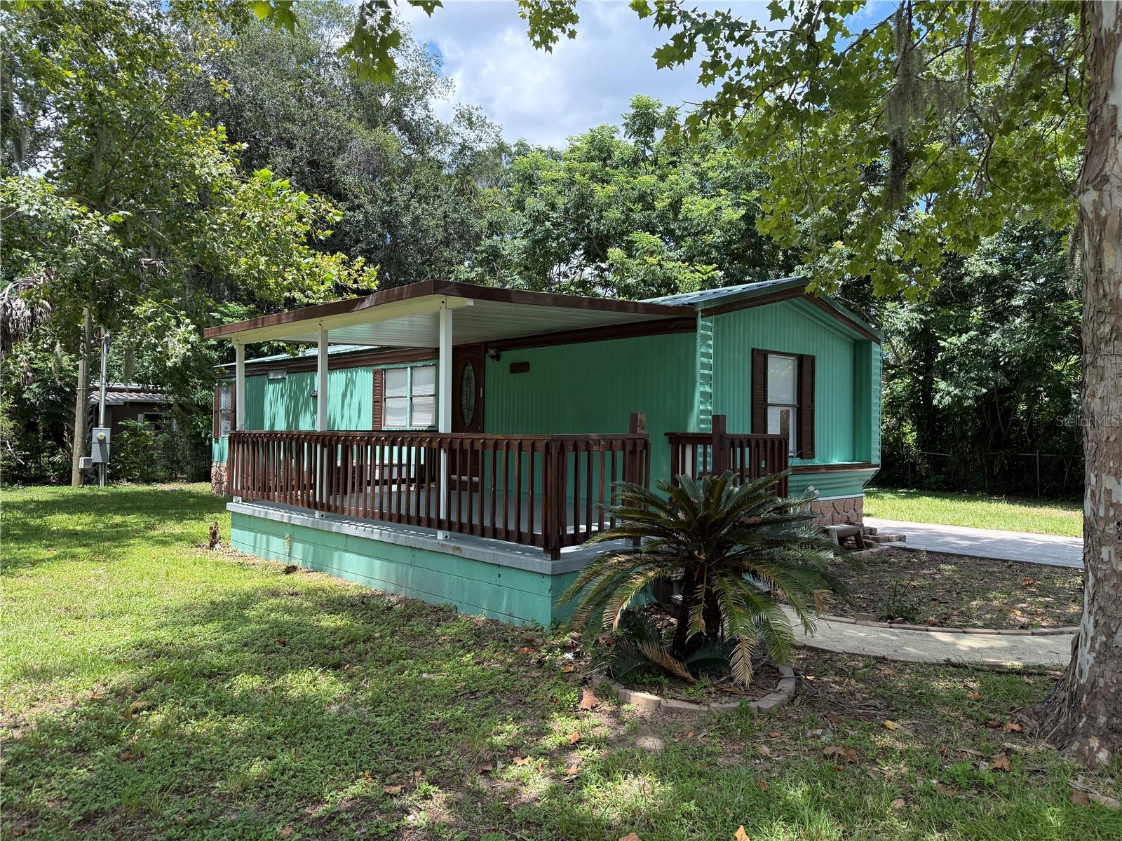Welcome to this beautifully updated mobile home, ideally set on a .20-acre corner lot backing up a wooded space for added privacy. Located at a short drive from I-75, Downtown Ocala, WEC, grocery shopping and restaurants for convenient accessibility. The GOLDEN HOLIDAY MHP is known for its family-friendly environment and peaceful community. Step into a bright and inviting living room seamlessly connecting with the well-appointed kitchen, ideal for family gathering and tasteful meals around the breakfast nook. The Bedrooms offer generous space for a King bed or 2 twin beds (as shown in the pictures). A dedicated laundry room makes chores simple and efficient, while the attached carport provides covered parking and easy access. Grab your favorite cup and relax at the spacious front porch while enjoying the Florida weather. The included utility shed provides extra storage for your toys and gears. This move-in ready property comes with furniture, metal roof, and laminate flooring for easy maintenance. No lot rent, No HOA, No lease restrictions. Scheduled your showing today and say hello to your new home!