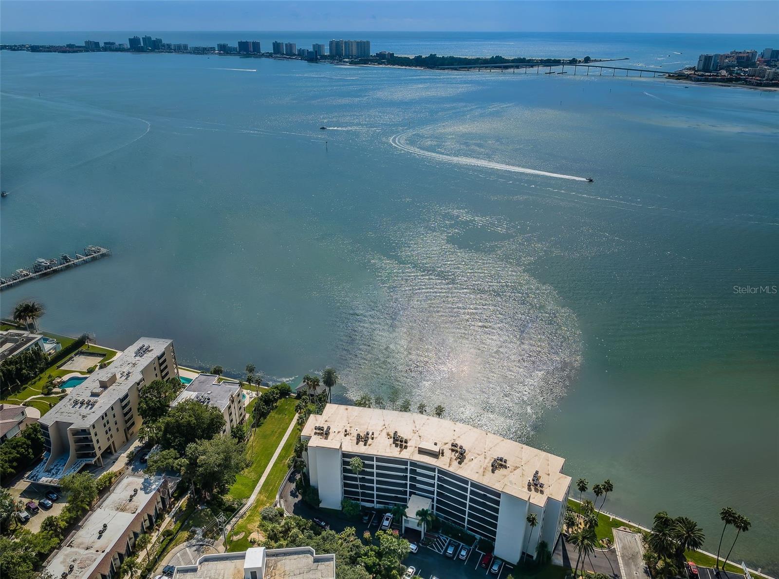 This sumptuous 2-bedroom, 2 full bath WATERFRONT CONDO boasts expansive gulf and intracoastal views, nightly sunset spectacles, and luxurious amenities, bordered by swaying palm trees. In addition to the home’s 1,425 heated SF, there is a spacious, tiled balcony. Accessible via sliders from both the master suite and the stunning living room, this venue is the ideal space to start your day (whether that’s with a rich cup of coffee or a yoga mat) and is the place to be for alfresco dining and entertaining. As for the living room, it is sublime. Natural light shines on the gleaming crown molding reflecting off the polished ceramic flooring. The adjacent dining room’s conversation piece is the exquisite built-in. Masterfully constructed, it is highlighted by recessed lighting, shelving of various dimensions, and granite-topped cabinetry, all poised to display infinite arrangements of your treasured collectibles and photos. Between the welcoming foyer and this fabulous dining space, you’ll find the contemporary (and brilliantly UPDATED) kitchen. From the tray ceiling to the lustrous backsplash to the granite tops to the flush mount lighting, not a detail was overlooked. Glass shelving/cabinet doors and decorative niches add architectural interest along with a built-in bar that’s ideal for your beverage fridge, a built-in desk for party planning, and a convenient breakfast bar (with storage). An LG Smart Appliance Package includes a french door refrigerator (with craft ice); all complemented by a huge pantry. The master suite is a delightful retreat. Presenting million-dollar vistas, its UPDATED ensuite is beautifully appointed. Recessed lighting shines down on a glass-walled shower room, granite countertops, and elegant fixtures while the cleverly designed walk-in closet features ample shelving, built-in cabinetry, and a charming vanity. The second bedroom is dressed in sleek plantation shutters accompanied by a graceful ceiling fan. Besides a huge closet and striking accent wall this space is a multi-functional one that can serve as: a guest suite, a home office, a study, or the idyllic meditation chamber; it awaits your unique purpose. The tile surround and flooring of its bath create a lovely ambiance. The thoughtfully crafted in-unit laundry room offers bars for hangers, open shelving for supplies, and drawers for storage, all encircling the slick and stackable LG WashTower. Textured, luxury vinyl tile runs throughout the common areas. Hurricane impact front windows and motorized storm shutters serve the balcony. Motorized blinds on all windows are WiFi-ready. Additional UPDATES include a NEW A/C system and water softener.. Viewpoint on the Bay has RECENTLY UNDERGONE ITS OWN RENOVATIONS with this impressive list: BRAND-NEW exterior building paint, building roof PLUS the painting of the lobby, stairwells, railings, balconies, and front doors; ALL done in 2025. You’ll also find NEW railings on the 5th and 6th floors, as well as NEW pool baths, and NEW landscaping. The parking lot was REPAVED (2023), and the NEWER community seawall erected in (2022). The HOA reserves are funded, SIRS is complete in addition to the Milestone Inspection. This slice of the incomparable Clearwater is a spectacular enclave that offers easy access to the local restaurants, retail, and the singular beauty of this region of Florida.