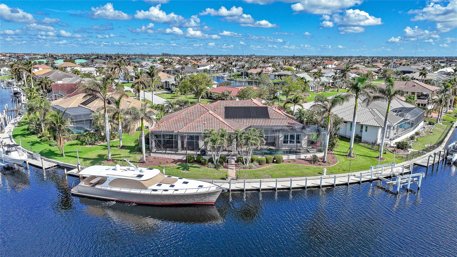 Set on an exclusive tip lot with direct sailboat access to Charlotte Harbor via Buckley Pass, this exceptional home offers the ultimate in waterfront living. Boasting 198' of concrete seawall, a 180' dock with water/electric, and a 25,000 lb. boat lift, this is a boater's paradise. Designed and built by Sandstar Homes, this custom residence exudes timeless elegance and unparalleled craftsmanship. With 4 spacious bedrooms, 4 bathrooms, a 3-car garage, and a dedicated office/den, this home is designed for both comfort and luxury. Over 5,000 square feet of meticulously planned living space showcase stunning details, including a grand foyer that opens to a great room with a soaring tray ceiling, tile and engineered hardwood floors, and a sleek ribbon gas fireplace. Expansive sliding doors lead to the outdoor pool/lanai area, offering sweeping water views for year-round enjoyment. The formal dining room features wet bar, perfect for entertaining, and the office/den, with French doors, offers privacy and versatility. Step into the heart of the home an exquisite chef’s kitchen that effortlessly blends style and function. Stunning Granite countertops and a complementary backsplash set the stage, while a spacious center island with elegant pendant lighting provides both form & function. Custom-designed Wellborn soft-close hardwood cabinets/drawers offer ample storage, and the expansive walk-in pantry and separate butler’s pantry ensure every culinary need is met. A convenient pot filler adds to the kitchen’s thoughtful design, while top-tier stainless steel appliances including a Wolf 48” Double Oven Dual Fuel Range and Sub-Zero refrigerator cater to the most discerning chefs. A cozy breakfast nook with fishbowl windows offers picturesque views of the pool and serene waterfront canal. The attention to detail is evident in the luxurious primary suite, which features private access to the cabana/pool area and offers an unparalleled retreat. Two stunning custom walk-in closets provide ample storage, while the spa-inspired bath includes a Roman shower with dual shower heads, a jetted soaking tub, and his-and-her Travertine vanities that exude elegance. The guest quarters are equally impressive, with 3 spacious bedrooms that offer comfort and privacy. The beautifully designed guest bathrooms feature oversized tiled walk-in showers, ensuring family and friends experience the same level of luxury throughout. The outdoor living space is truly an entertainer’s paradise. A stunning cabana area, featuring a striking stone wall and built-in gas fireplace, seamlessly flows into the fully-equipped outdoor kitchen. Complete with a Wolf grill, sideburner, ice maker, refrigerator, and seating for 6, this space is ideal for alfresco dining and gatherings. Just beyond, the covered lanai offers breathtaking views of the heated, saltwater Nautilus pool and spa, creating a serene and luxurious oasis. The expansive brick paver flooring, large screened enclosure with an integrated mosquito misting system, and unparalleled water views further enhance the tranquil ambiance of this remarkable outdoor retreat. The laundry room leads to an expansive, oversized 3-car garage with epoxy flooring and abundant storage space. The home is equipped with a security/fire alarm system, tankless water heaters, water softener, whole-house generator, 500-gallon buried LP tank, durable tile roof, solar panels, hurricane-rated windows/shutters and so much more.