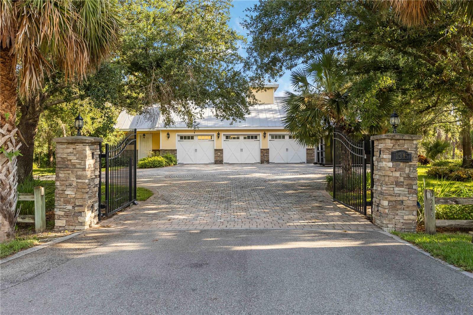 Discover a rare opportunity to own a privately gated waterfront estate on over two lush acres along Fox Creek in the equestrian-friendly community of Mission Valley Estates. Ideal for professionals, families, or hobbyists, this property offers both elegance and functionality. Beyond the wrought-iron gates lies a separate carriage house featuring an air-conditioned four-car garage, workshop, full bath, kitchenette, and an upstairs bonus room—perfect for an office, guest space, or hobby area. This additional 2,195 sq. ft. is ideal for storing cars, RVs, boats, and more. The stately main residence spans over 6,300 sq. ft., with 4,741 sq. ft. under air. It features four spacious bedrooms (with potential for a fifth), four and a half bathrooms, a library with built-ins, a media room, and beautiful architectural details including crown molding, vaulted ceilings, and wrap-around porches. The updated kitchen boasts soft-close cabinetry, stainless appliances (including dual refrigerators and a new range), and a walk-in pantry with wood shelving. Entertain with ease in the large dining room, enhanced by custom built-ins, wainscoting, and a wood-burning fireplace. Outside, enjoy a resurfaced saltwater pool and spa, pavered lanai, and a peaceful setting with boatable water access and a private dock. Tucked away yet conveniently located near Gulf beaches, top-rated schools, parks, shopping, dining, and highways—this hidden gem offers the perfect balance of privacy, luxury, and accessibility. Come see it today.