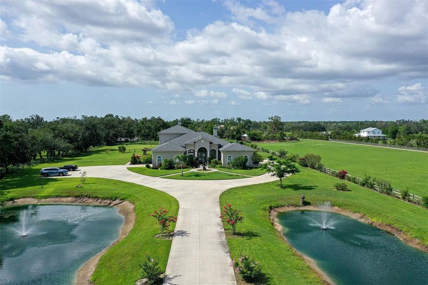 Visualize what quiet luxury looks like. It starts with passing through the electronic gate, down the long, tree-lined driveway, nestled between lighted ponds with twin fountains, leading towards this stately 5,000+ sq ft home on over 5 acres. The entry courtyard features a welcoming custom bronze fountain and a brick-paved portico leading to a double French door entry. Sweeping into the living room with 12-foot ceilings, tile floors, and a fireplace, you'll pass the private office with a built-in desk and shelves. The formal dining room features a majestic coved ceiling and French doors to a side patio. The modern kitchen with stainless appliances offers an enormous amount of cabinet and counter space, opening to a breakfast nook and family room with a second fireplace. A media room, tech closet with Wi-Fi tower, and a half bath are steps away. Beyond that is a private in-law suite currently used as an office with a conference room/living room, bedroom, private bath, kitchenette, and private entry. Also located on the main floor is a luxurious primary bedroom suite with 2 generous closets and an ensuite bath, as well as a 2nd bedroom with an ensuite bath, a hobby room, and a laundry room. Located up the sweeping staircase are 3 bedrooms, 2 bathrooms, a small lounge area, a large storage room, and a covered balcony.  The screened-in pool offers two large lounging spaces and stone pavers overlooking the lush pasture out back. In 2020, the entire property underwent an extensive renovation, including, but not limited to, a new roof, plumbing, multiple HVC systems, new pool and spa, brick pavers, concrete driveway, multiple new fountains, fresh landscaping and sod, all windows older than 2018 were upgraded, electrical wiring replaced, all new flooring, all bathrooms and total kitchen were remodeled, giving this 5,000+ sf home an effective age of 2020. The owner also added a 24-kw whole-house generator, a reclaimed water irrigation system covering the entire 5-acre property, and a 500-gallon propane tank. This is an amazing home at an incredible price!