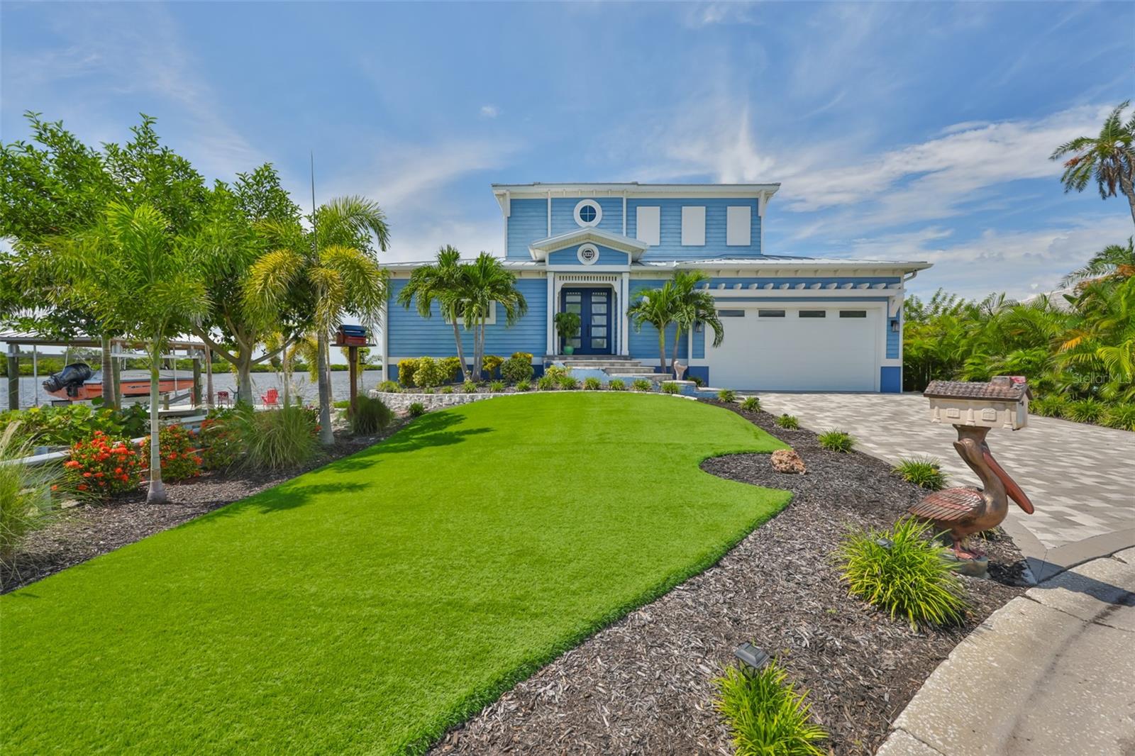 Welcome to 937 Birdie Way, a stunning 3-bedroom, 2.5-bathroom, two-story home with a 2-car garage perfectly positioned at the end of a quiet cul-de-sac. This modern coastal retreat offers panoramic views of Tampa Bay and sits on a deepwater canal with direct access to open water. Designed for the ultimate coastal lifestyle this property features a covered 15'x24' boat lift (10,000 lb capacity) and a private dock, making it a boater's dream. Enjoy year-round outdoor living with a sparkling heated pool and spa overlooking the Bay, a screened-in patio, and an upper balcony for breathtaking sunsets and unobstructed water views. Inside, the open-concept design showcases luxury finishes throughout. The gourmet kitchen boasts a striking two-toned design with a large gray island, white cabinetry, Frigidaire appliances, a gas range with pot filler, and marble-accented windowsills. The living room features a dramatic 20' sliding door that opens fully to the waterfront, an electric fireplace, tray ceilings, and custom details like rounded wall corners and oak wood stair treads. The first-floor primary suite is a true retreat, offering tray ceilings, dual vanities, a walk-in shower, a freestanding soaking tub, towel warmer, water closet, and a spacious walk-in closet complete with a built-in dresser and its own washer and dryer. Upstairs, a loft with balcony access anchors two guest bedrooms on opposite sides, while a guest bath with its own laundry hookup adds convenience. Obtaining the certificate of occupancy in 2021 with a metal roof, hurricane impact windows, and dual A/C systems, this home offers peace of mind along with modern luxury. Additional features include a propane gas system for the stove and tankless water heater, a 14-foot garage ceiling, and an elevated homesite at 12.3 feet with flood insurance under $560 per year. This exceptional property did not experience flooding during recent storms and is ready to deliver the best of Tampa Bay waterfront living.