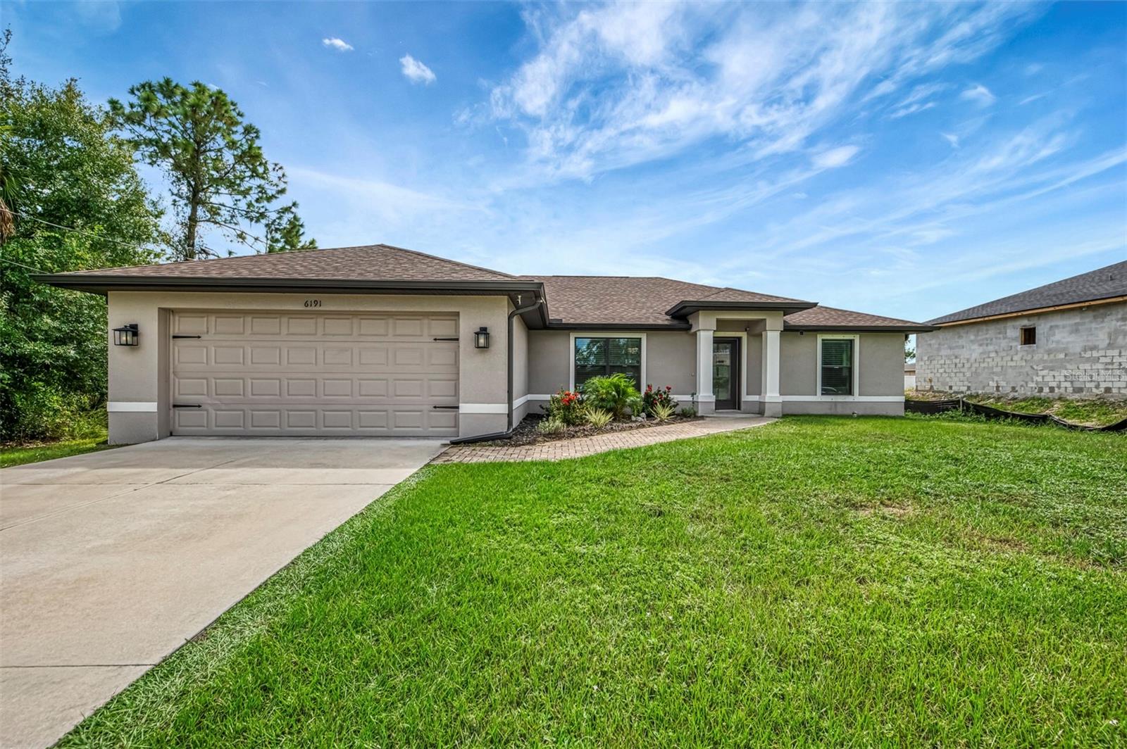 NORTH PORT ESTATES BEAUTY! Built in 2019 and offering nearly 1,700 square feet of upgraded living space, this 3-bedroom, 2-bathroom home—with an additional den or office featuring a decorative barn door that can easily serve as a 4th bedroom—delivers the perfect blend of style, comfort, and practicality. With a NEW ROOF (2023), no HOA fees, and no flood zone, this property is ready for worry-free living. Step inside and feel the open flow of cathedral ceilings and elegant plank tile flooring throughout. The great room seamlessly connects to a gorgeous modern kitchen, complete with a center island quartz breakfast bar, slow-close wood cabinetry with crown molding, subway tile backsplash, black stainless-steel appliances, and upgraded pendant lighting. Whether preparing a meal or entertaining, this kitchen makes it easy and enjoyable. The dining area’s French doors open to an oversized 12x37-foot covered lanai, overlooking a fenced backyard with room to relax, play, or garden. (Yes, the trampoline can stay!) Enjoy outdoor living all year long in privacy and peace. The primary suite is a showpiece with a tray ceiling, a large walk-in closet, and a luxurious ensuite featuring dual quartz sinks, a garden tub, and a multi-head shower. Both guest bedrooms are generously sized—13x11—with walk-in closets and ceiling fans. The guest bath includes a tub/shower combo and stylish finishes. Additional highlights include: indoor laundry with washer and dryer, brick paver driveway and walkway, full hurricane protection, newer well, updated A/C, water softener, and security cameras. Located in sought-after North Port Estates, you’ll enjoy the quiet country feel while being just minutes from city conveniences. Nearby Myakkahatchee Creek Environmental Park offers scenic walking and biking trails, horseback riding, fishing, and picnic areas. You’re also close to I-75, the new Sarasota Memorial Hospital, shopping, restaurants, and top local attractions. Move-in ready, beautifully maintained, and priced right—this home checks every box. Furniture is negotiable—schedule your private showing today!