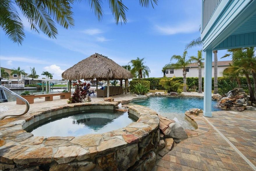 Situated on two lots in Hernando Beach, this waterfront retreat delivers a true resort-style experience at home.
From a heated lagoon-style pool and spa to private docks and multiple garages, every detail is designed for elevated coastal living.

Welcome to the ultimate waterfront lifestyle in Hernando Beach, where resort-style living meets everyday comfort. This elevated canal-front home offers an exceptional amount of space, privacy, and flexibility—creating a property that stands out from the typical waterfront offering.

Designed for both entertaining and functionality, the property features two separate two-car garages, providing ample room for vehicles, boats, golf carts, and recreational equipment. Whether you need storage, workspace, or room for all your coastal toys, this setup delivers versatility that is rarely found in this area.

Step outside to your own private retreat, where a heated lagoon-style pool and spa with a cascading rock waterfall create a true resort-like setting. Surrounded by expansive paver decking and multiple lounging areas, the outdoor space is designed to be enjoyed year-round. A fully outfitted tiki hut sets the stage for entertaining, relaxing, or enjoying sunset evenings just steps from the water. The private dock and multiple boat lifts offer seamless access for boating enthusiasts, making it easy to spend your days on the water and return home to a true backyard oasis.

Inside, the home offers a bright and open layout with a spacious great room that flows effortlessly into the kitchen and dining areas. Large windows and sliding glass doors frame the canal views and bring in natural light, creating a seamless connection between indoor and outdoor living. The kitchen features an oversized island, generous cabinetry, and modern finishes, making it both functional and ideal for gathering.

The primary suite offers a peaceful retreat with private balcony access overlooking the canal—perfect for morning coffee or unwinding in the evening. The en-suite bathroom includes a walk-in shower, freestanding soaking tub, and a clean, coastal-inspired design. Additional bedrooms and bathrooms provide flexibility for guests, family, or work-from-home needs.

With its combination of double lot positioning, heated pool and spa, expansive outdoor living, multiple garages, and direct water access, this property delivers a rare opportunity to own a true waterfront lifestyle in Hernando Beach. Whether you're seeking a primary residence, second home, or investment property, this is Florida living at its finest.