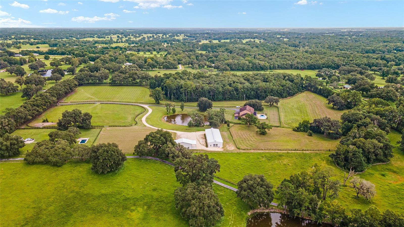 THIS IS AN AMAZING NEW PRICE FOR THIS PROPERTY!!
Possible Owner Financing*
Welcome to this 25+acre Equestrian Estate off the end of Millionaire's Row in Marion County's Horse Capital of the World. The 11 stall center aisle block barn is ready for your show horses with new paint, new stall doors, new beautiful barn doors with matching stall window shutters and all new rubber pavers. There's an inside wash stall, grooming stall, new half bath, new shower, new septic, tackroom, feed room and office with new tongue and groove ceilings. New barn driveway is shared with a brand new 30x50 shop with roll up doors, great for storing your tractor, trailer, jumps, hay, etc. There are a few huge pastures with lush grass, two auto waterers, a run in shed and plenty of room to add an arena. Across the pond with fountain is the 5,800 sq ft two story brick residence with 5 bedrooms, 4 full and 2 half baths, with first floor primary bedroom. A grand entrance with open foyer and wooden staircase. First floor primary with two walk in closets with built ins, soaking tub, large shower and his and her vanities. A chef's kitchen with granite countertops, two walk in pantries, eat in kitchen, island and bar seating. Huge lanai accessed through multiple rooms by french doors looks out on the saltwater pool with water feature and solar heating. This is a beautifully constructed home with high ceilings, thick intricate crown molding and ceiling medallions, textured walls and a stone fireplace. A truly elegant home and peaceful setting surrounded by horse farms. Less than 10 minutes to the WEC Jockey Club, 15 minutes to HITS and 20 minutes to the famous World Equestrian Center. This property sits in the highly desired NW quadrant and has so much to offer.