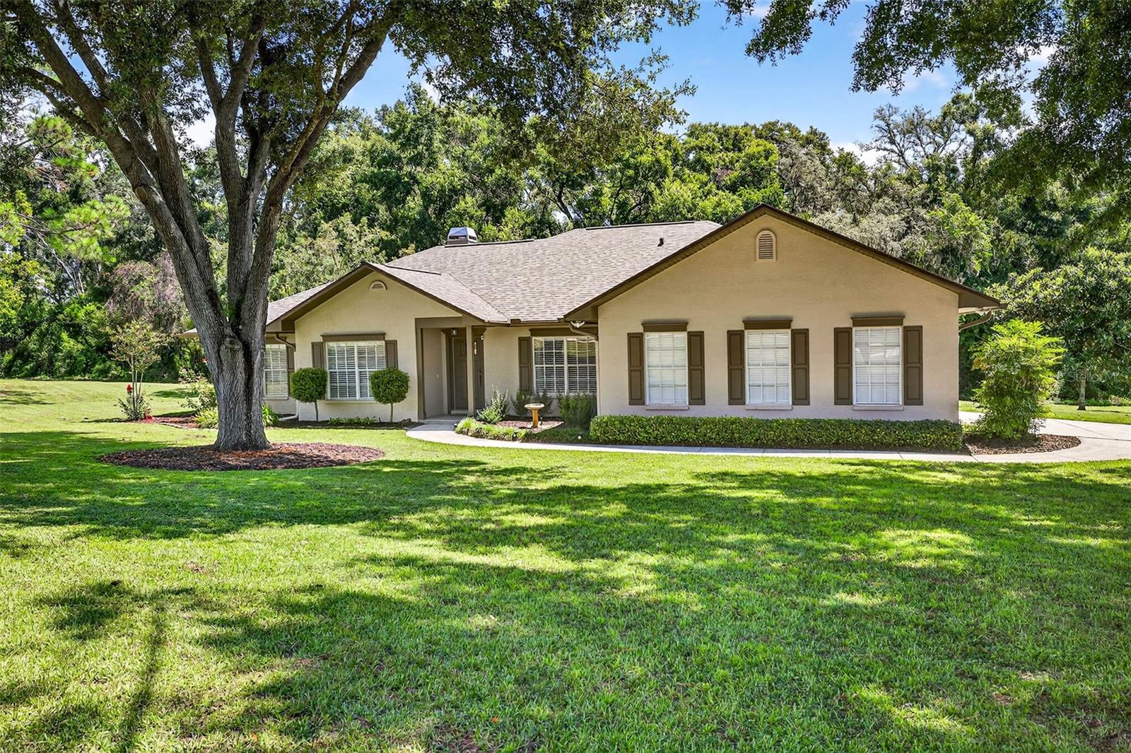 Nestled on a spacious 1-acre lot with mature trees and lush landscaping, this charming 4-bedroom, 2.5-bath home offers the perfect blend of privacy, comfort, and elegance. Located at the end of a quiet cul-de-sac, the property provides both seclusion and safety, making it an excellent choice for families or those seeking a peaceful retreat.A welcoming front entry with manicured hedges sets the tone for the inviting interior. Inside, the foyer opens to warm hardwood floors, custom wainscoting, and tasteful wallpaper accents that add character and charm. A versatile den with French doors offers the ideal space for a home office, library, or media room. The formal dining room is bright and sophisticated with chair rail detailing, updated lighting, and large windows that fill the space with natural light.At the heart of the home, the living room impresses with vaulted ceilings, hardwood floors, and a stunning stacked-stone fireplace that serves as the centerpiece. French doors line the back wall, opening to the screened pool area and flooding the space with natural light. Connecting seamlessly to the kitchen and breakfast nook, creating a warm and welcoming atmosphere for family gatherings or entertaining guests.The kitchen is a true highlight, featuring sleek white shaker cabinetry, quartz countertops, a marble tile backsplash, and modern brass hardware. A large peninsula with bar seating makes it easy to serve and entertain. Just off the kitchen, the breakfast nook offers a casual dining space with large windows overlooking the pool, making every meal feel special.The primary bedroom offers generous space, warm wood flooring, and soft natural light from multiple windows. A neutral color palette creates a calming atmosphere, while private access to the pool area enhances the indoor–outdoor lifestyle. The en suite bathroom is designed for both function and relaxation, featuring a dual-sink vanity with ample storage, a soaking tub surrounded by tile, and a separate walk-in shower with neutral stone finishes. Large windows with faux wood blinds allow natural light to brighten the space while maintaining privacy, creating a spa-like setting within the home.Step outside and discover a private backyard oasis designed for both relaxation and entertaining. A spacious covered lanai provides a shaded retreat, complete with ceiling fans to keep you comfortable year-round. This inviting space opens directly onto the expansive screened pool enclosure, where sparkling blue water is surrounded by ample deck space for lounging or dining.The pool area overlooks the lush one-acre lot, framed by mature trees and green space that enhance both privacy and serenity. Whether enjoying a quiet morning coffee on the lanai, hosting a barbecue with friends, or swimming under the screened enclosure, this backyard is perfectly suited to Florida living. Roof: May-2025. Exterior paint: June-2025. New pool screen June-2025. Pool deck resurfaced June-2025. New front door June-2025. Garage floor resurfaced August-2025.